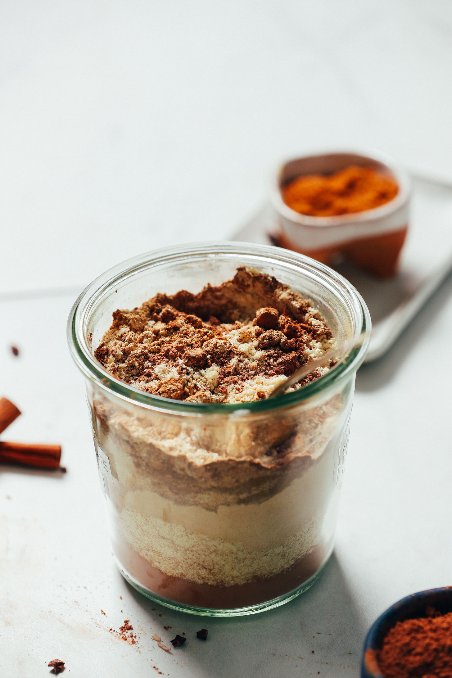 Spoon resting in a jar filled with ingredients for making our Adaptogenic Hot Chocolate Mix