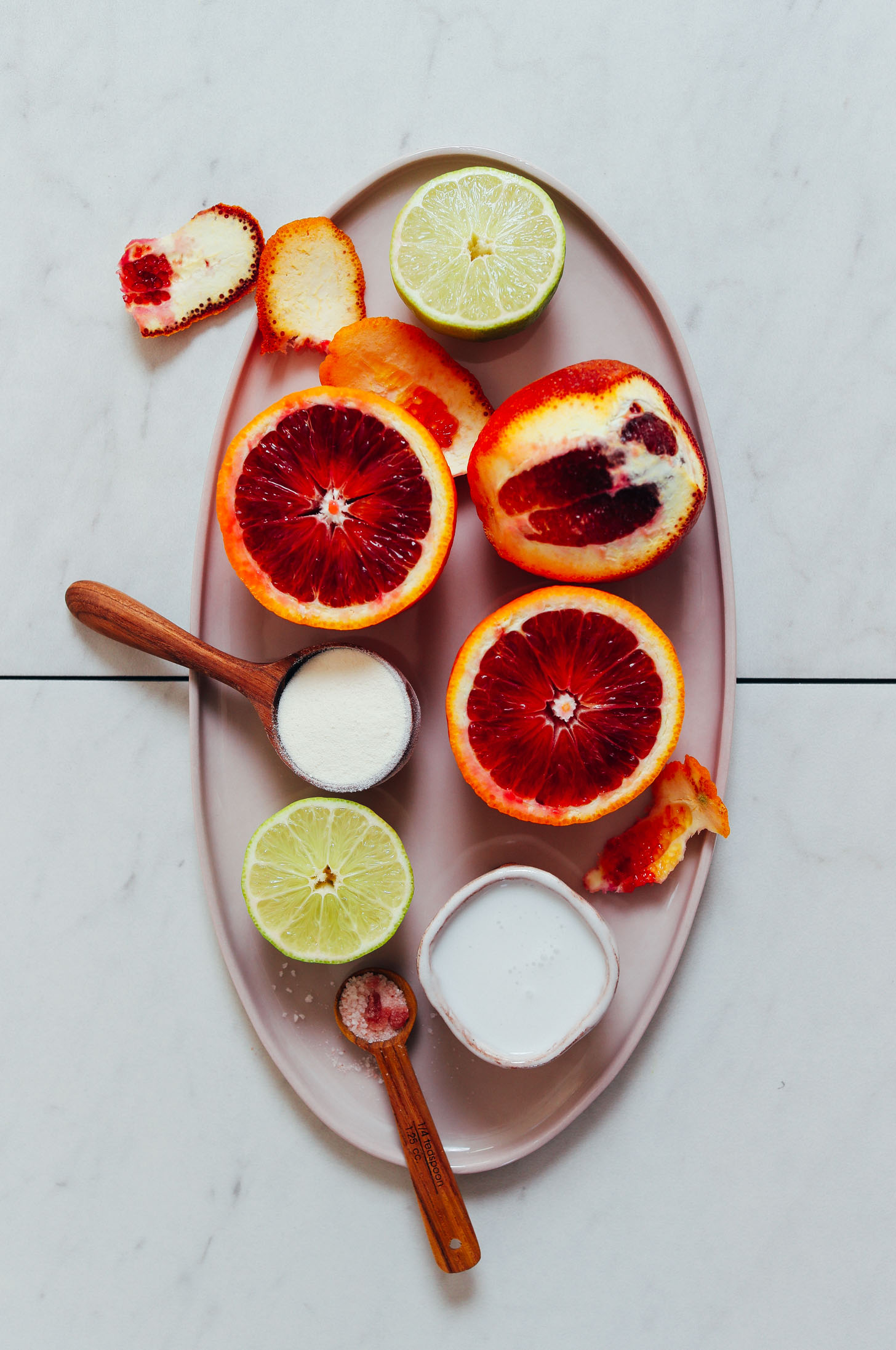 Platter of limes, blood oranges, coconut milk, collagen, and pink salt for making our Creamsicle Smoothie recipe