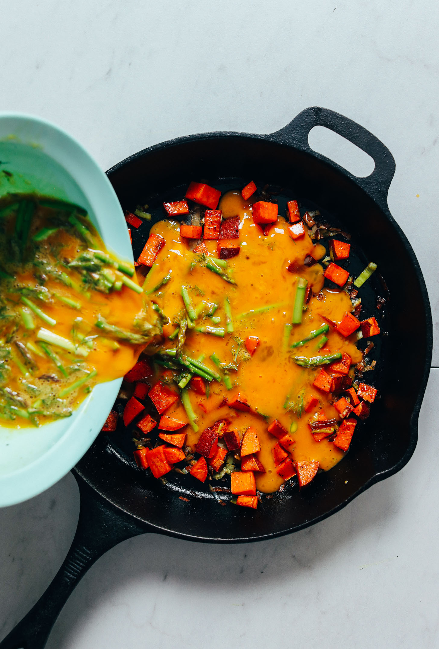 Pouring egg mixture into a cast iron skillet for our Spring Frittata recipe