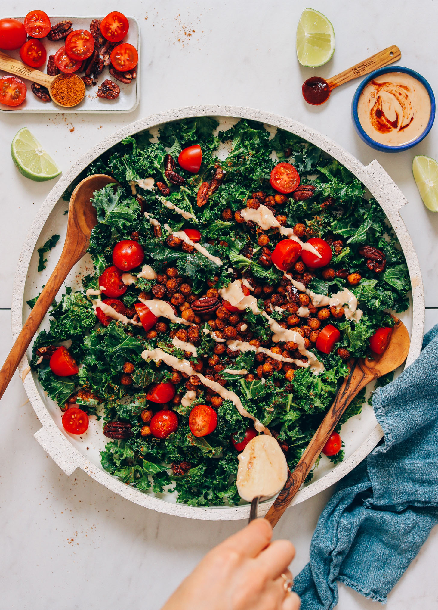 Using a spoon to drizzle Adobo Dressing onto our Chickpea Chopped Kale Salad