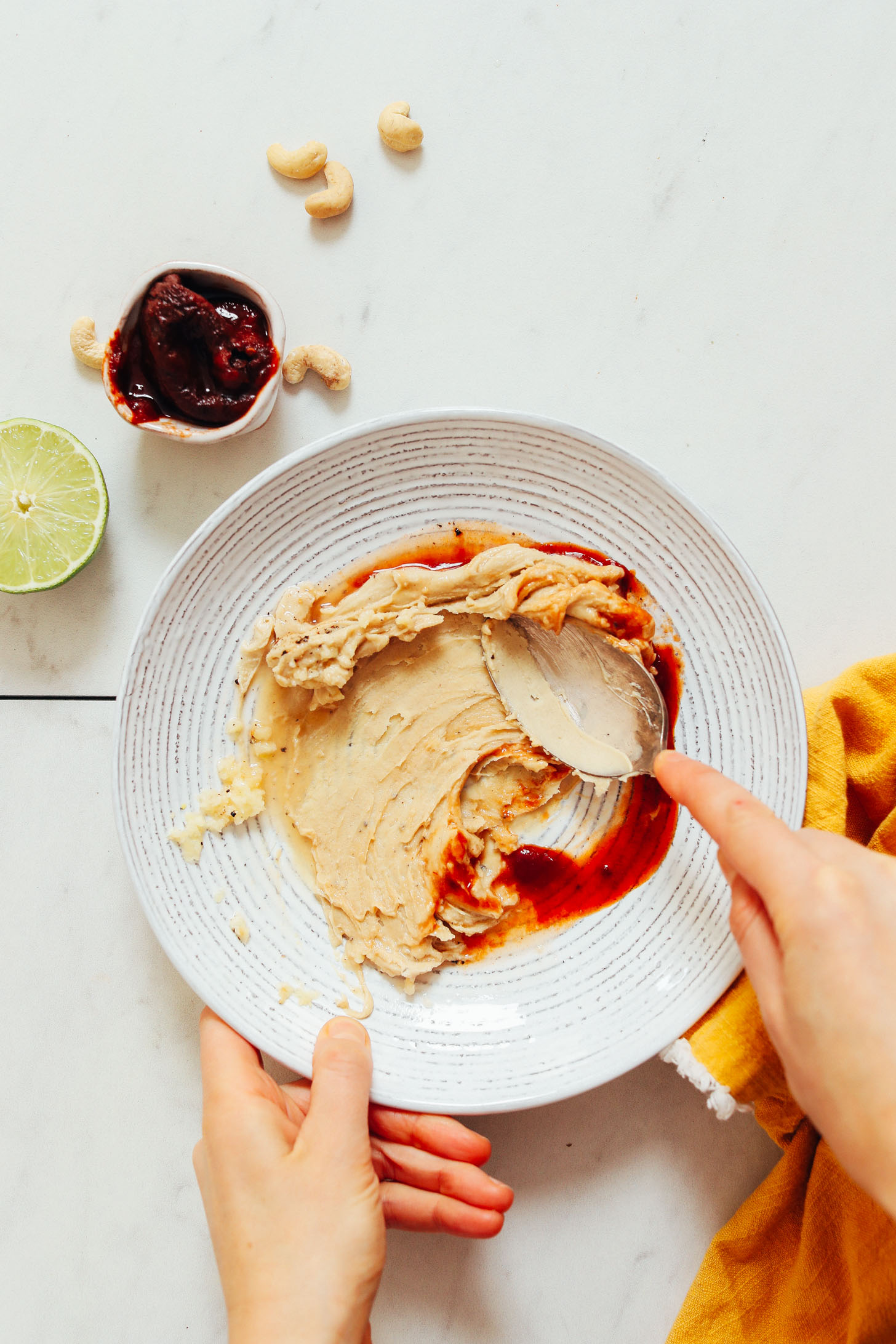 Using a spoon to stir adobo sauce and cashew butter for our Smoky Chipotle Dressing recipe