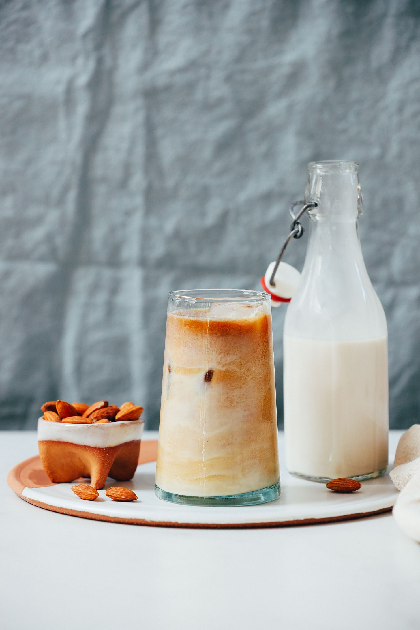 Bowl of almonds next to an iced coffee and container of almond milk coffee creamer