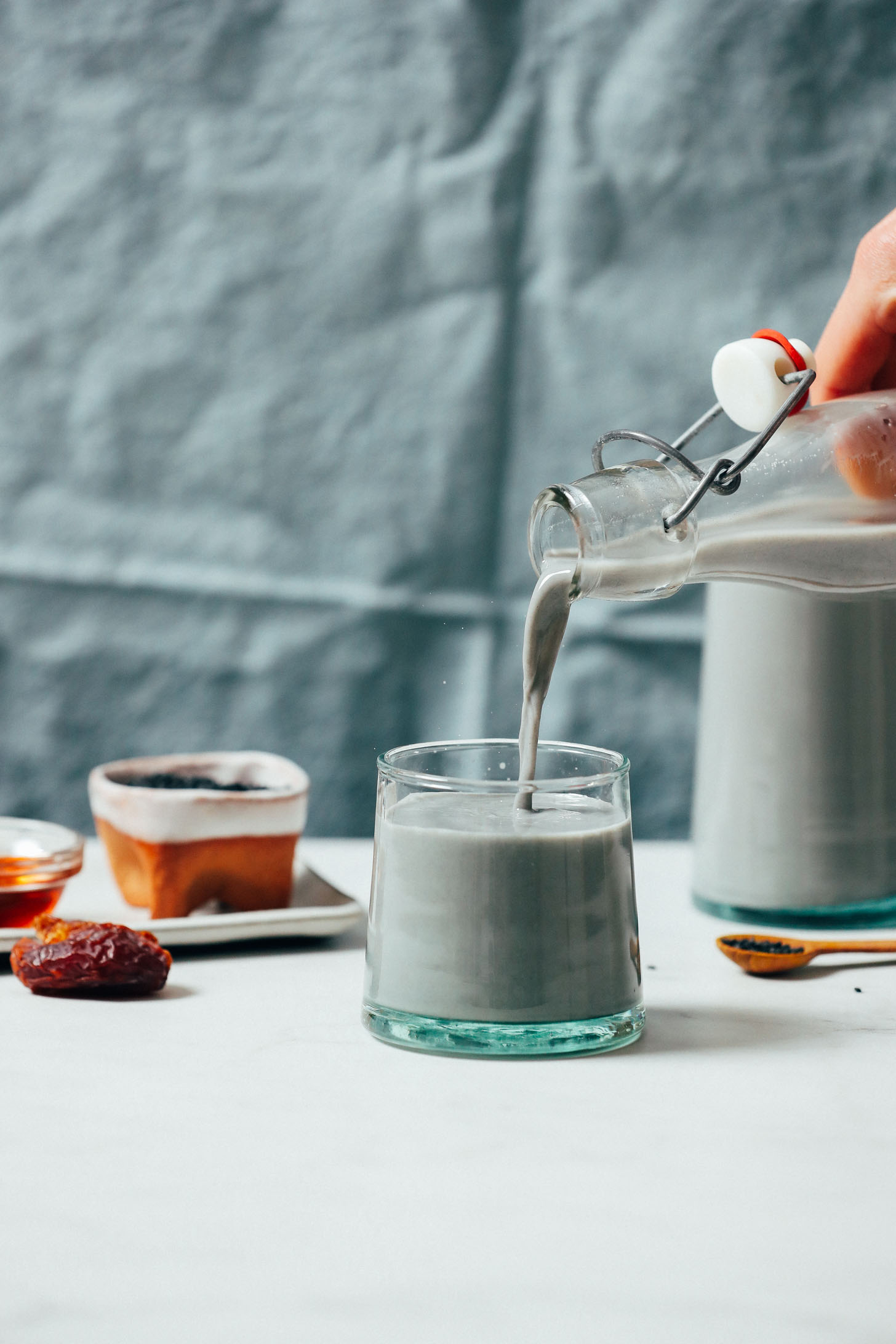 Glass of Creamy Black Sesame Milk next to ingredients used to make it