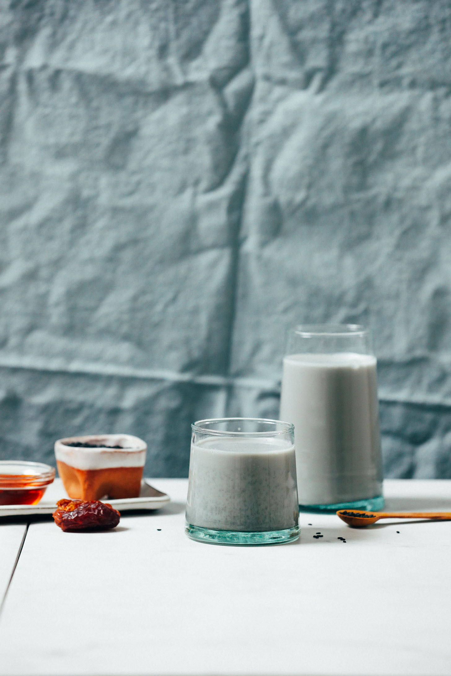 Two glasses of Black Sesame Milk next to ingredients used to make it