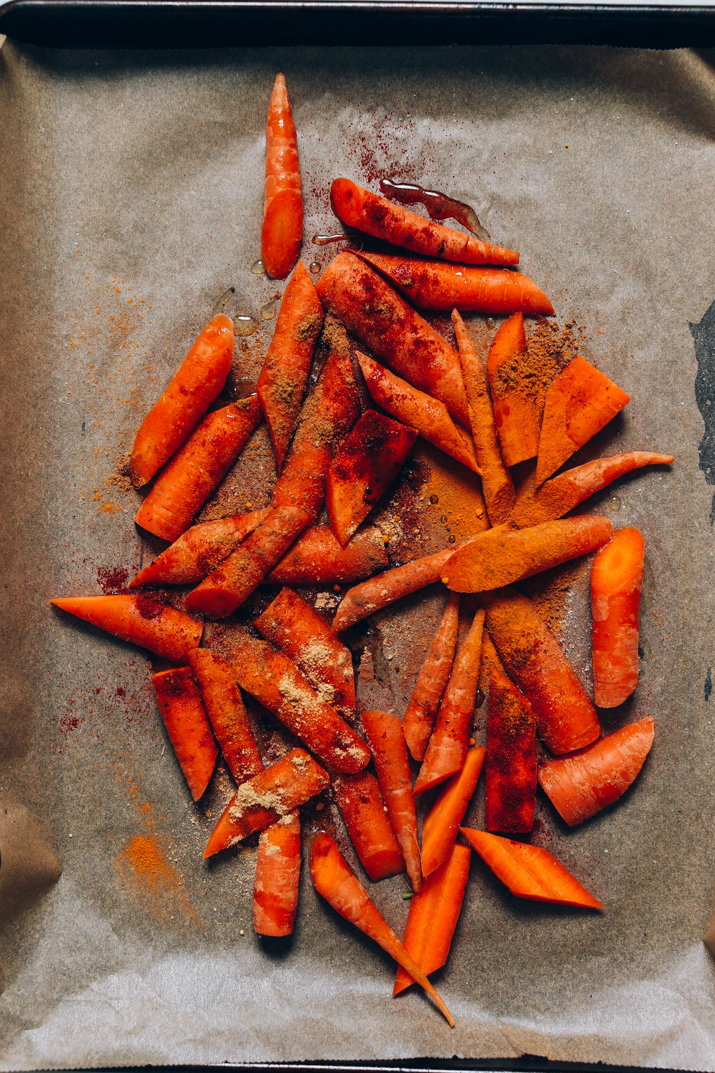 Baking sheet of sliced carrots topped with Moroccan spices and avocado oil