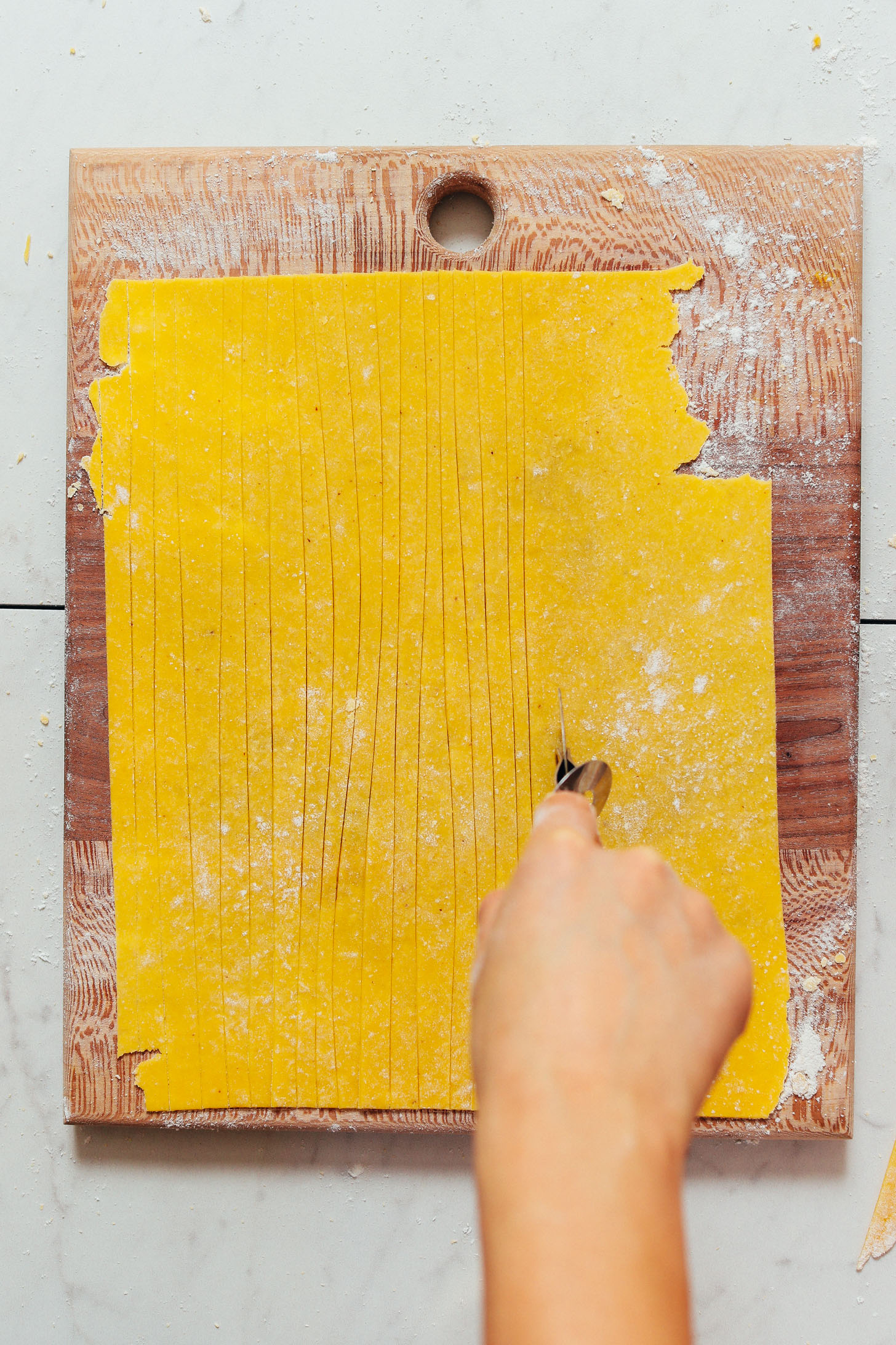 Using a pizza cutter to slice homemade Gluten Free Egg Pasta