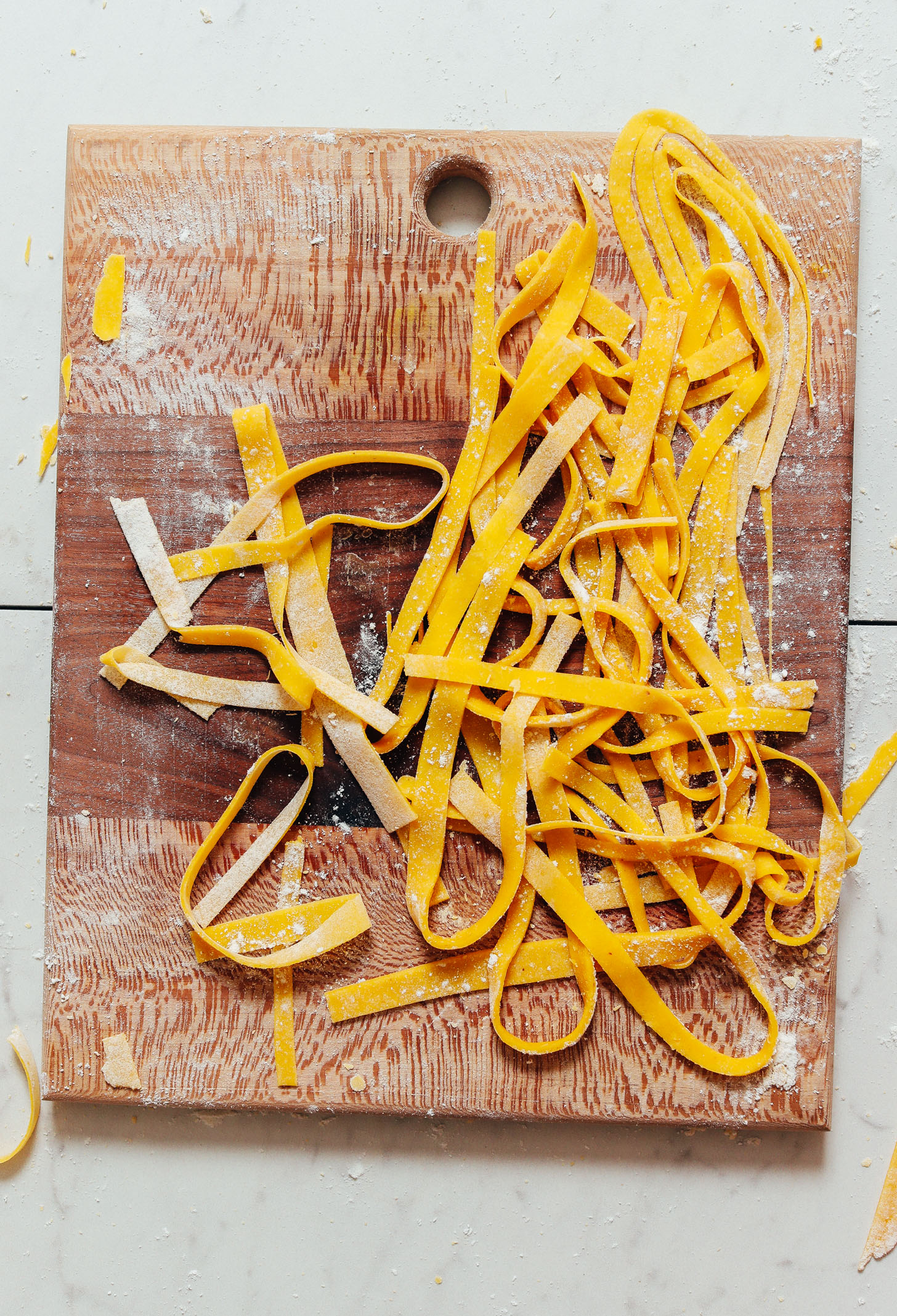 Cutting board of homemade Gluten Free Egg Noodles before cooking