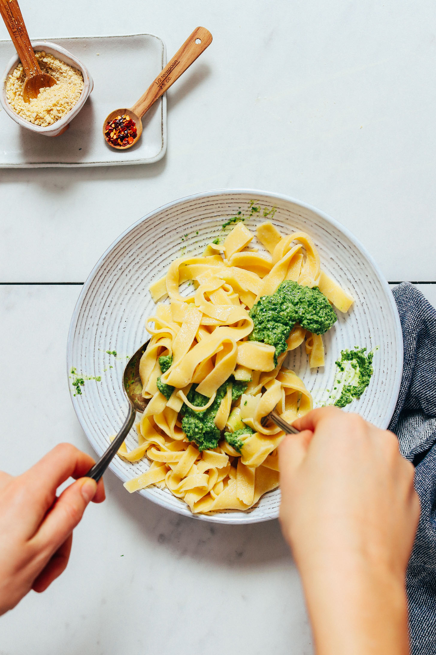 Mixing dairy-free pesto and homemade gluten free noodles in a bowl