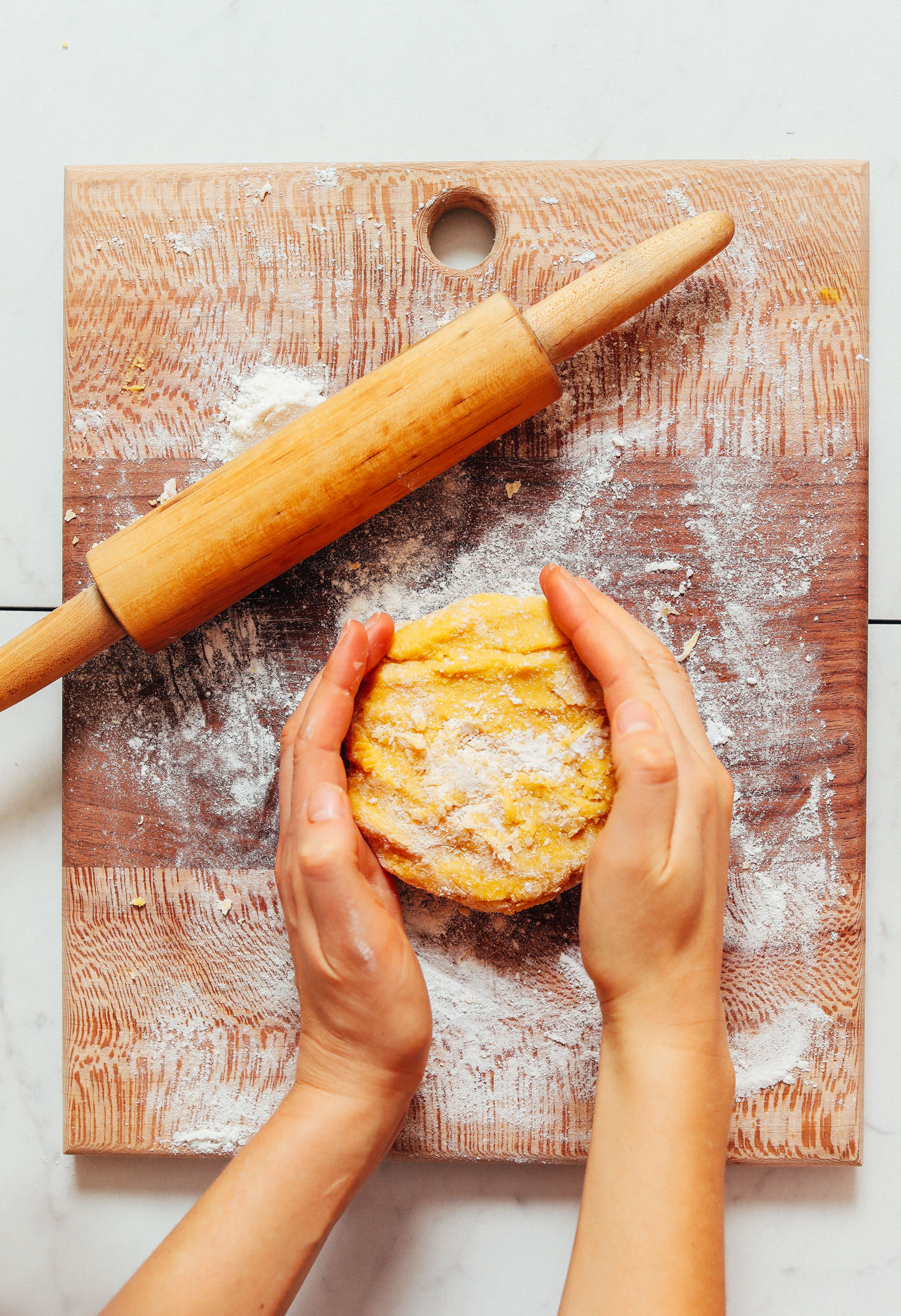 Circle of Gluten Free Pasta Dough on a floured wood cutting board