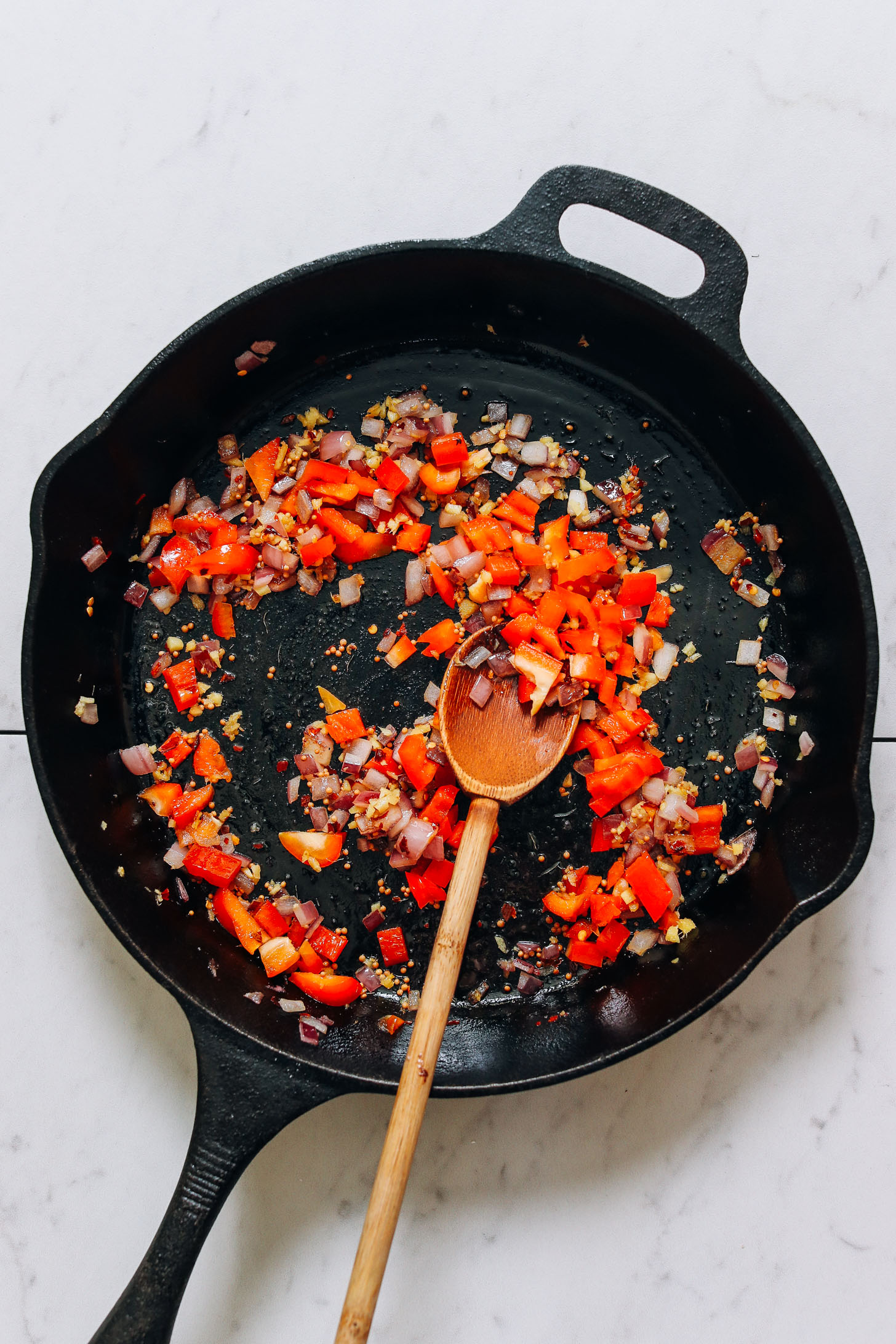 Sautéed onion, bell pepper, and spices in a cast iron skillet for making our Potato Aloo Sabzi recipe
