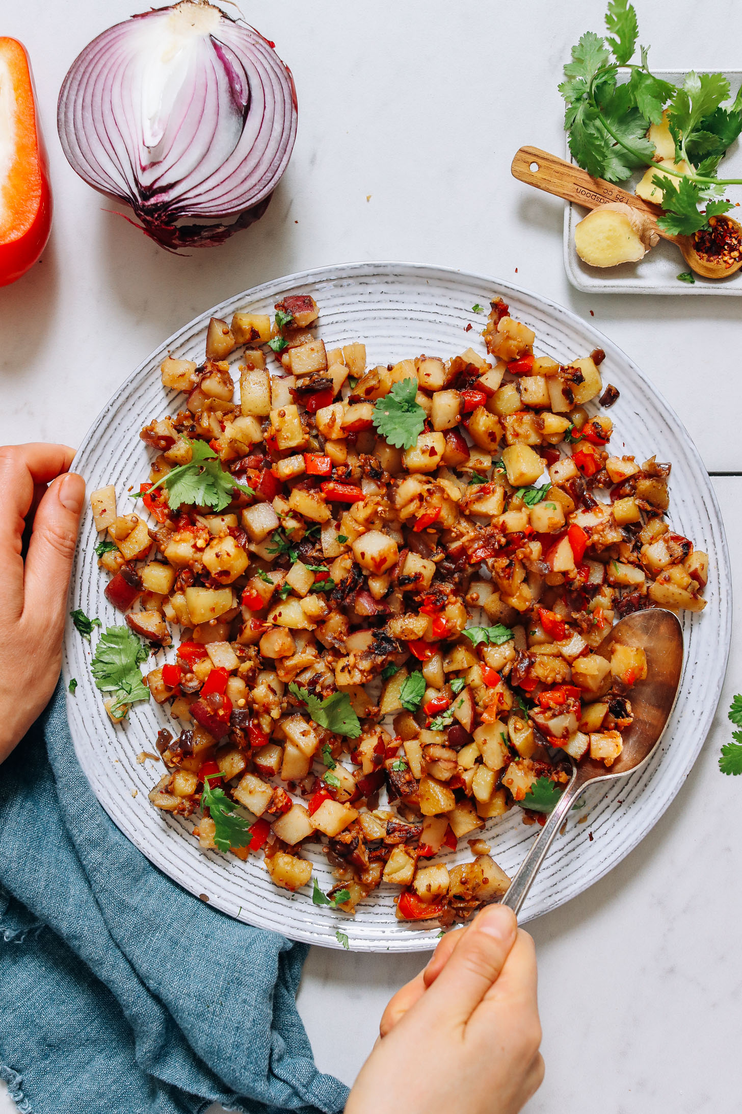 Plate of Potato Aloo Sabzi surrounded by ingredients used to make it
