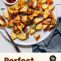 Large plate of our Perfect Roasted Potatoes recipe beside a bowl of ketchup