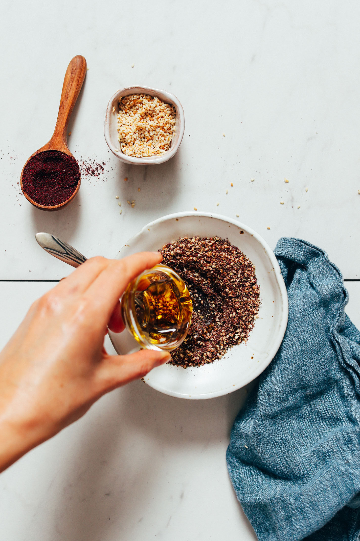 Pouring olive oil into a bowl of homemade za'atar seasoning