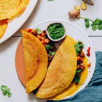Plate of moong dal dosas stuffed with sabzi and green chutney