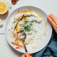 Using a spoon to stir a bowl of Zesty Dill Yogurt Sauce
