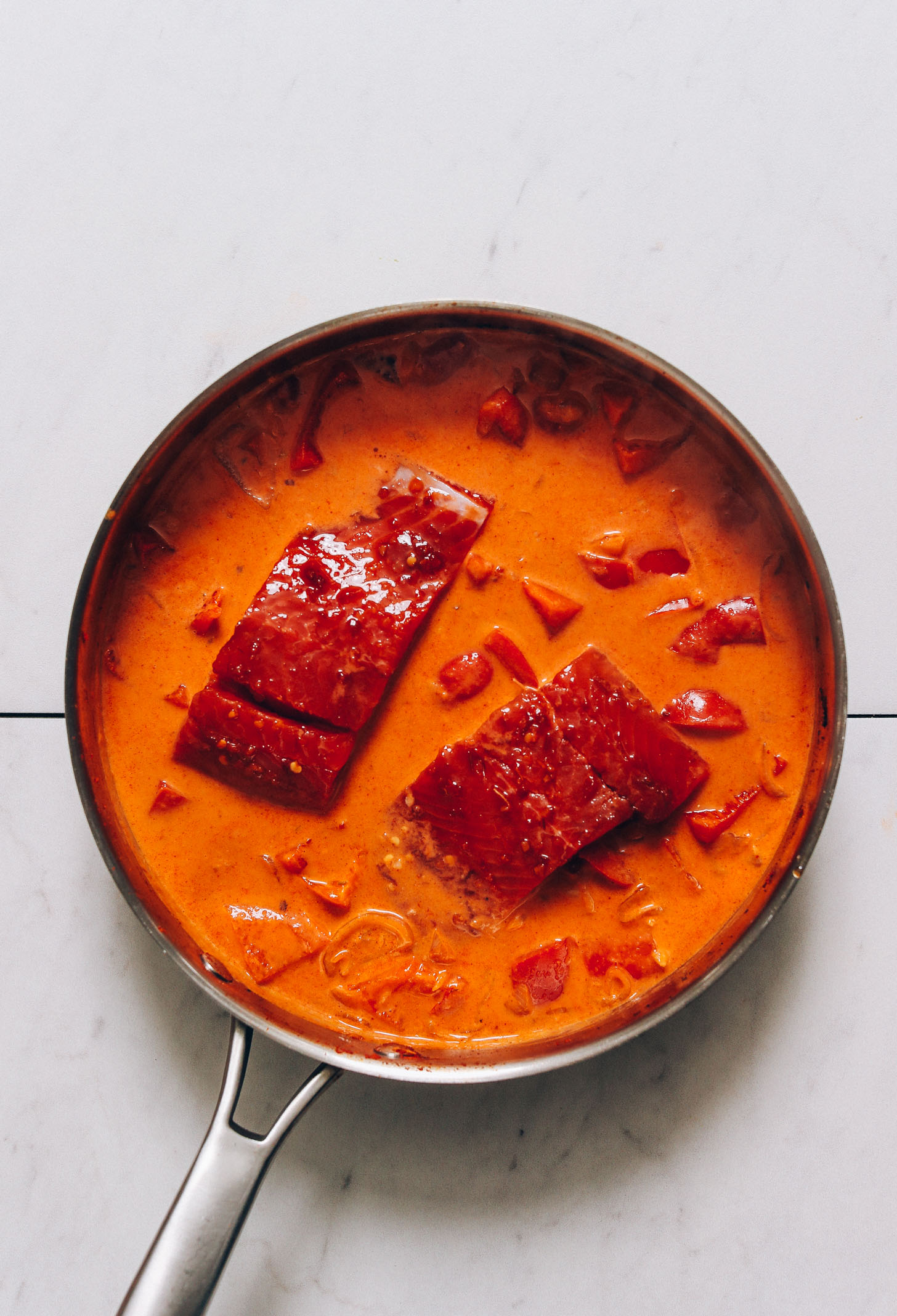 Skillet of salmon filets and vegetables for making Salmon Red Curry