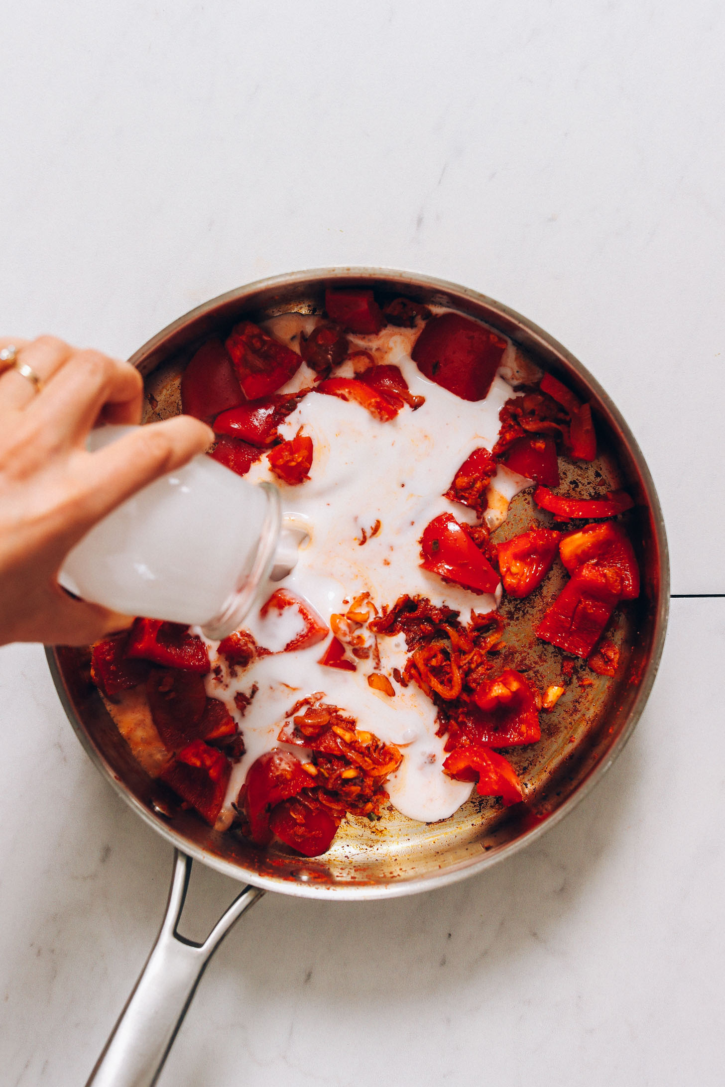 Pouring coconut milk into a pan to make our Salmon Red Curry recipe