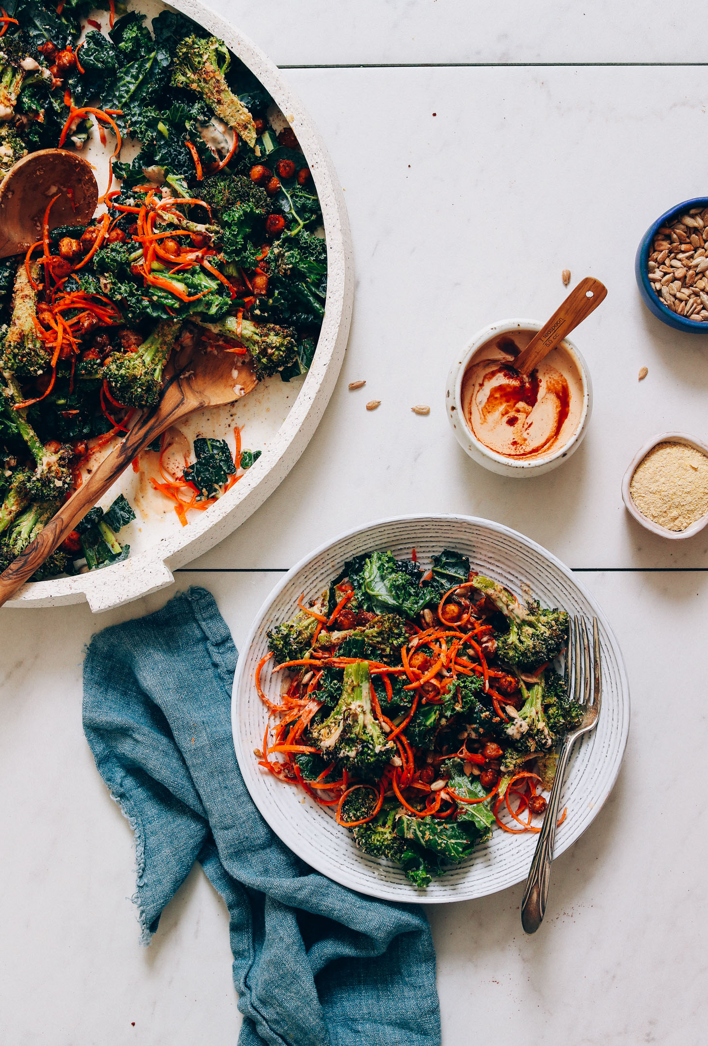 Bowl and platter of Cheesy Roasted Broccoli & Chickpea Kale Salad beside a bowl of Smoky Chipotle Dressing