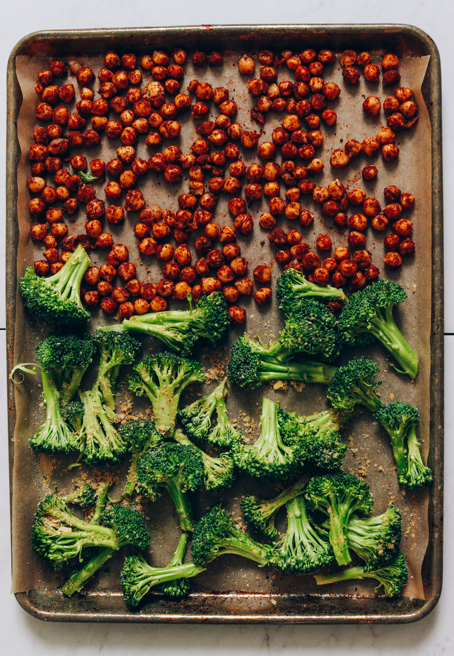 Parchment-lined baking sheet of broccoli and seasoned chickpeas