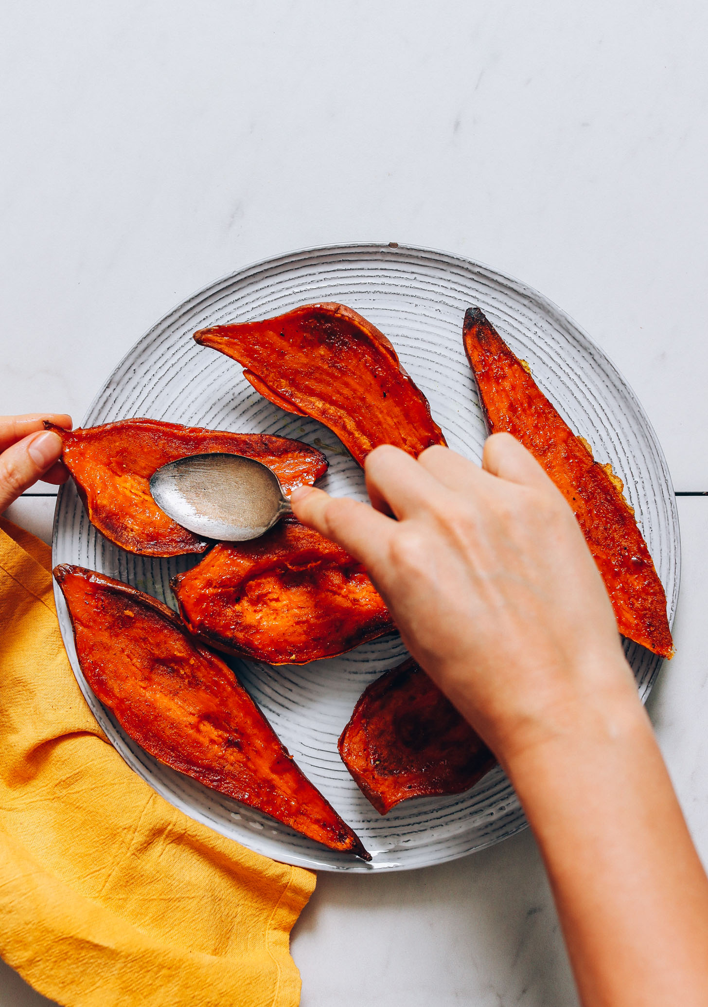 Using the back of a spoon to gently smash down the sweet potato flesh