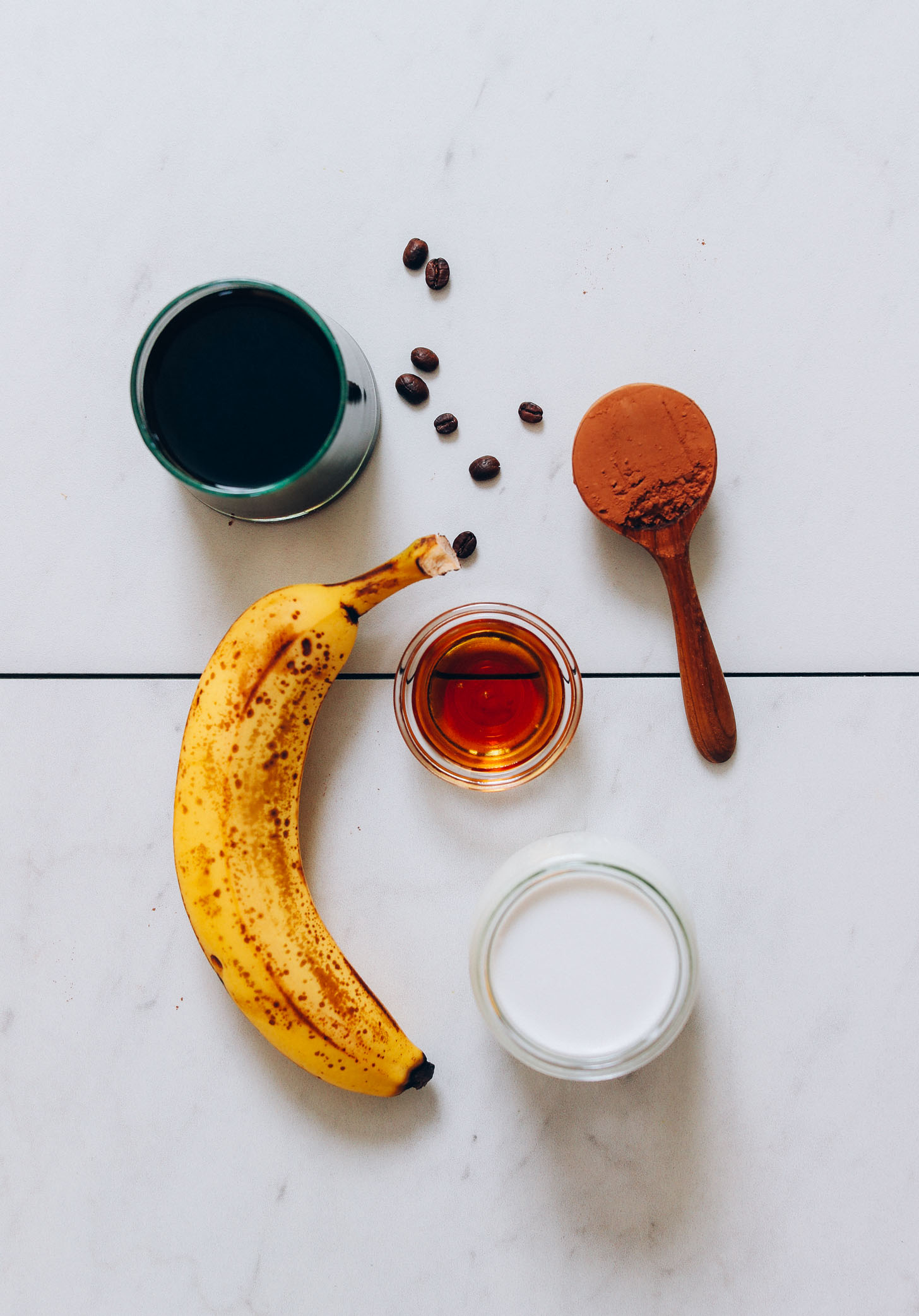 Coffee, banana, maple syrup, cacao powder, and coconut milk for making our Creamy Cold Brew Smoothie recipe