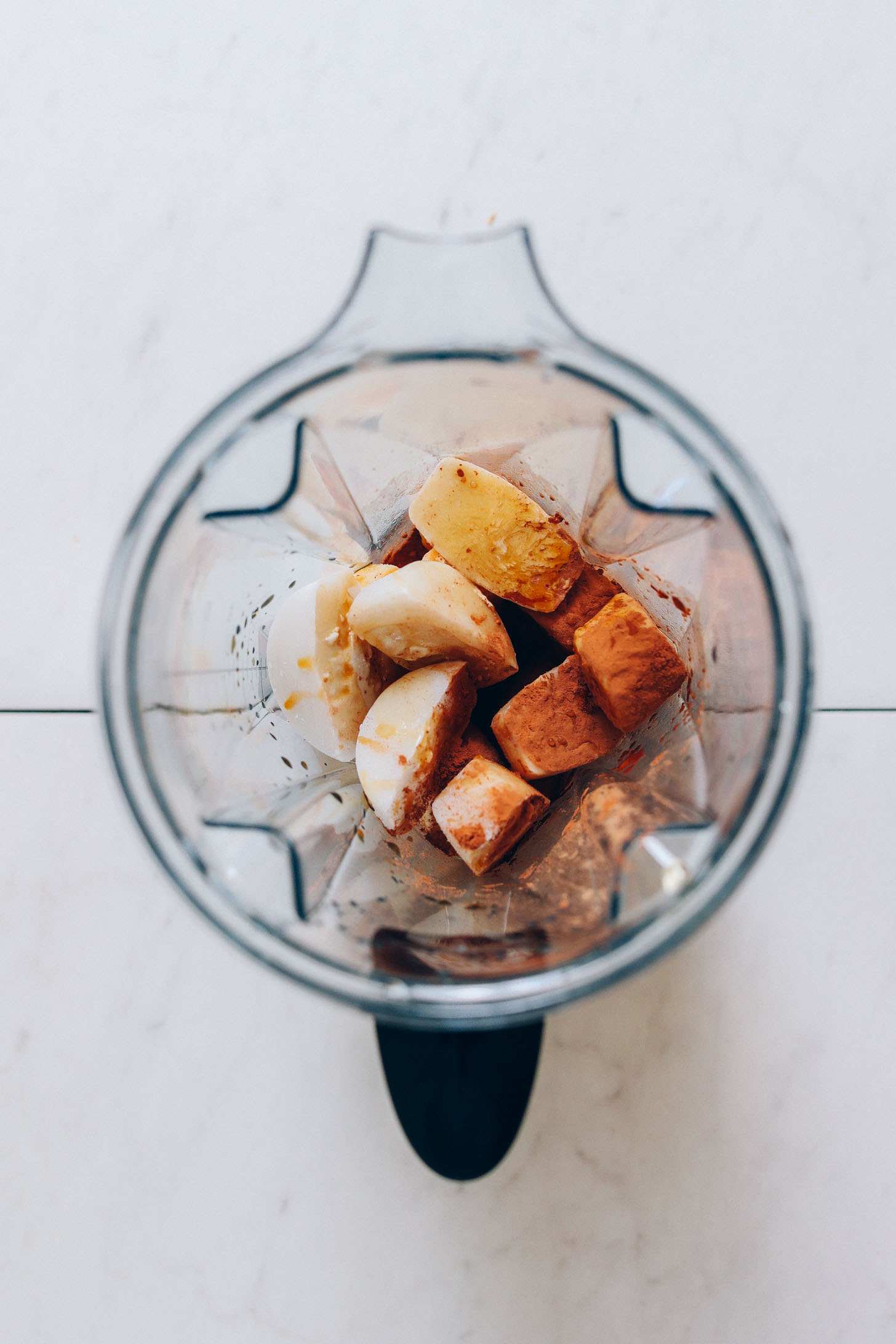 Bananas, coconut milk ice cubes, and other ingredients in a blender for making our dairy-free Coffee Smoothie recipe