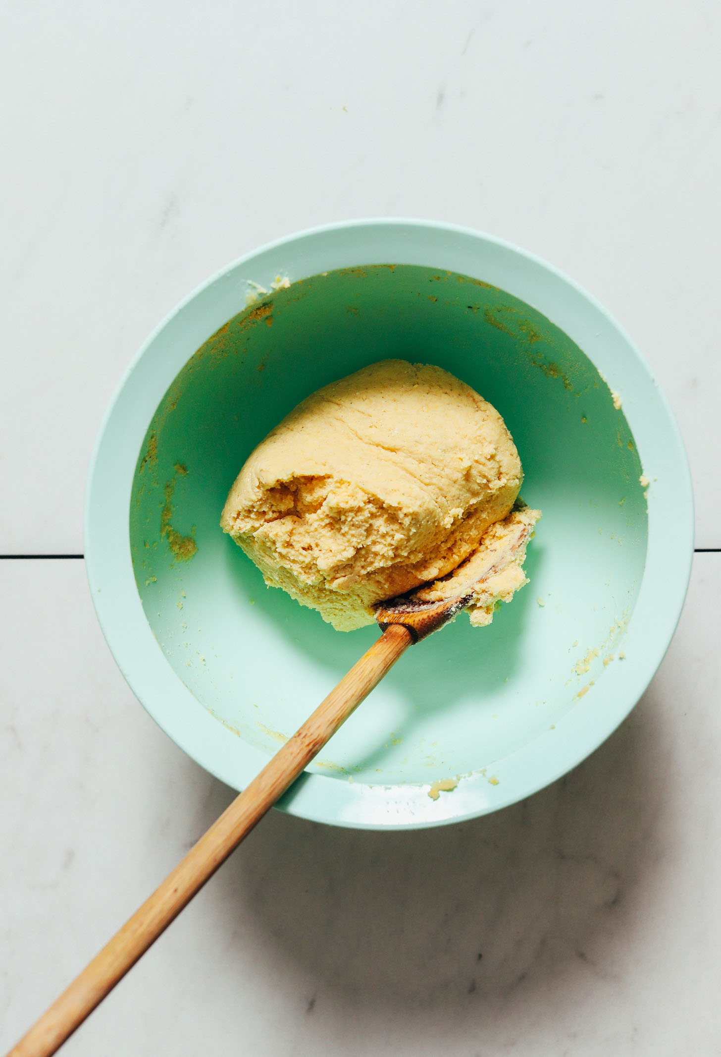 Wooden spoon and a ball of corn tortilla dough in a mixing bowl