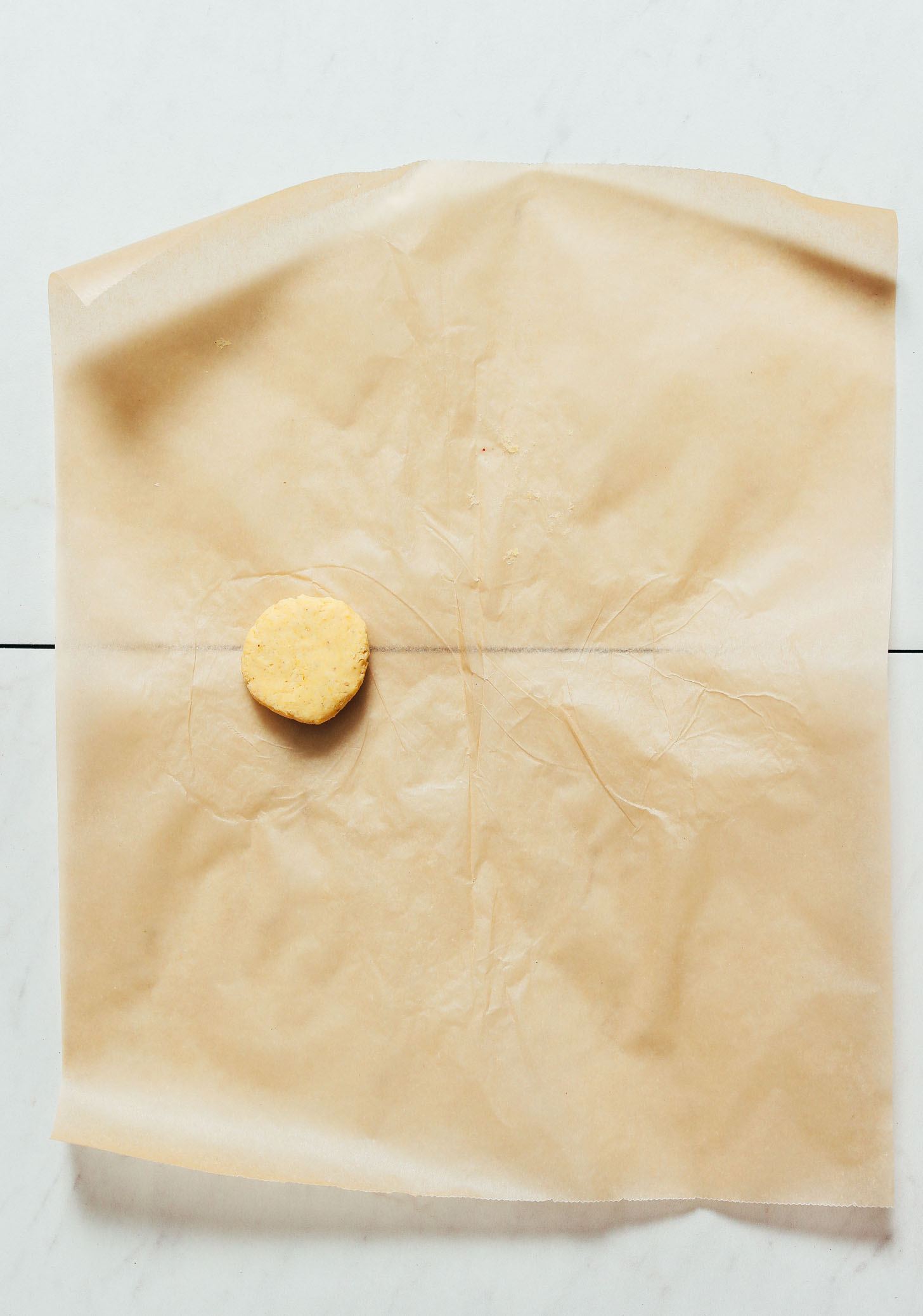 Ball of corn tortilla dough on a piece of parchment paper to show How to Make Tortillas without a tortilla press