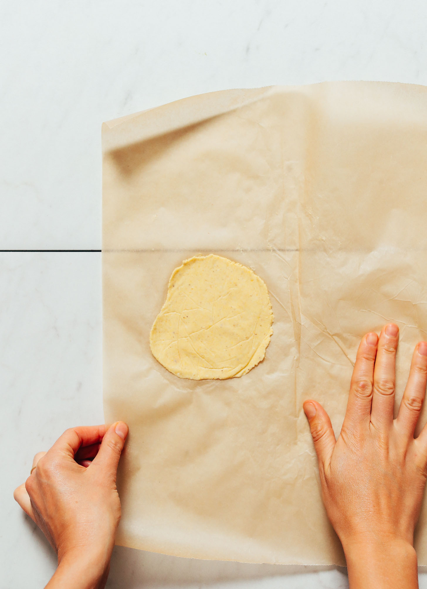 Corn tortilla on a piece of parchment paper for our tutorial on How to Make Tortillas