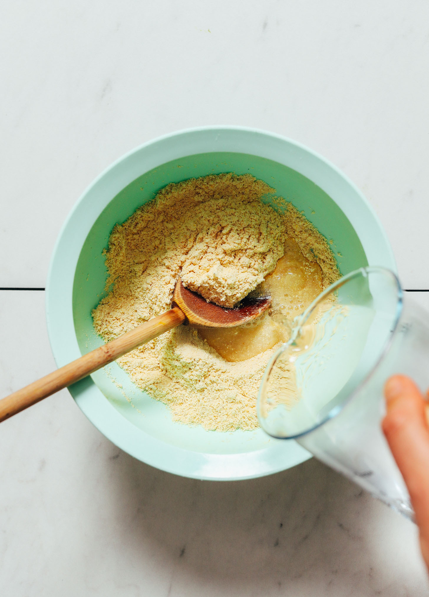 Adding water to a bowl of masa harina for homemade corn tortillas
