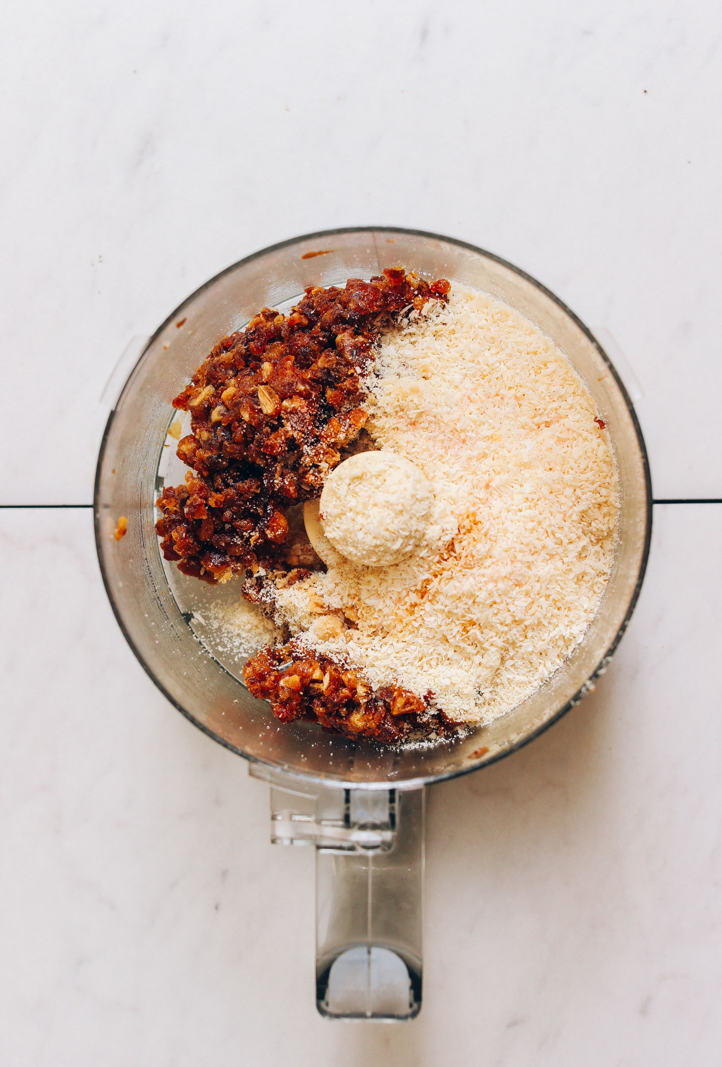 Food processor of almond flour, desiccated coconut, and chopped pitted dates