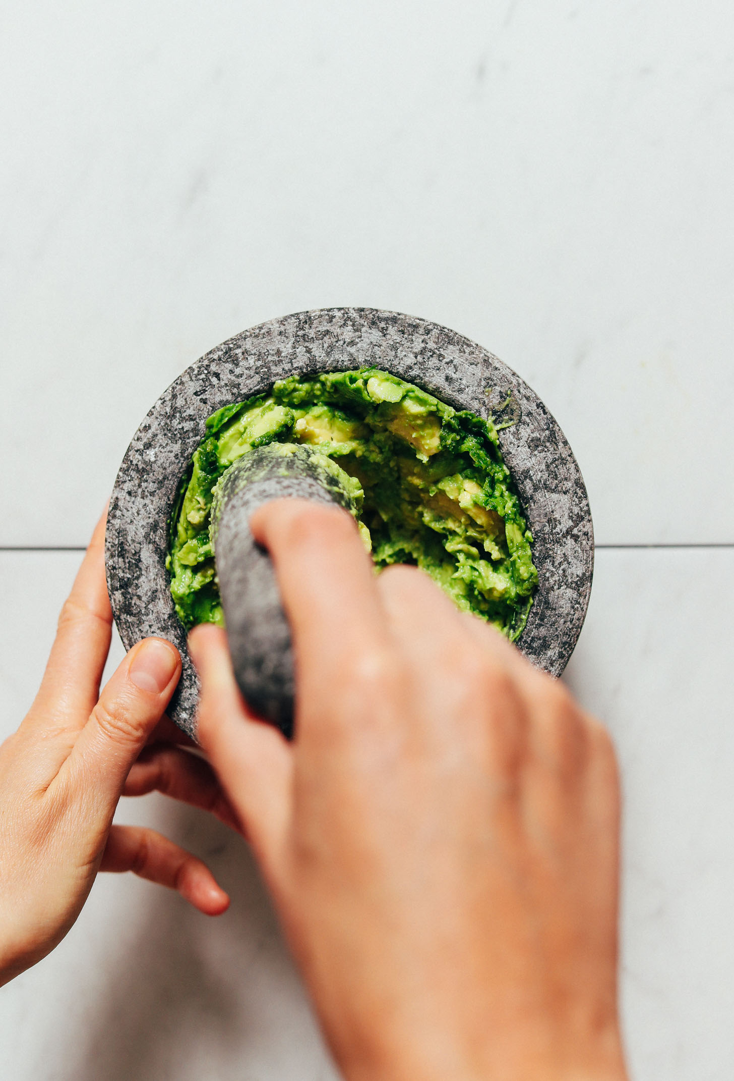 Using a mortar and pestle to smash avocado for making guacamole