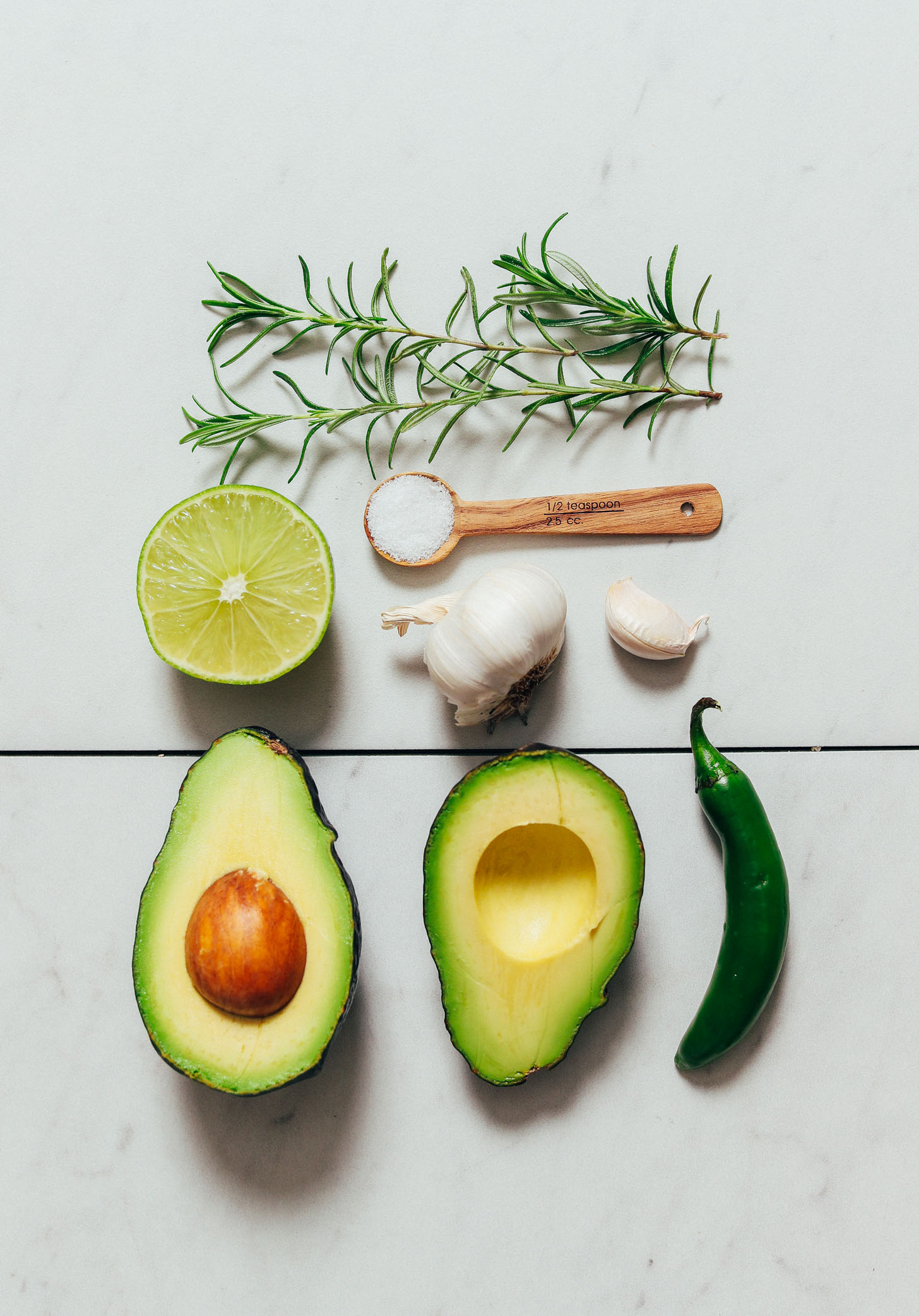 Avocado, serrano, garlic, salt, lime, and rosemary for making guacamole