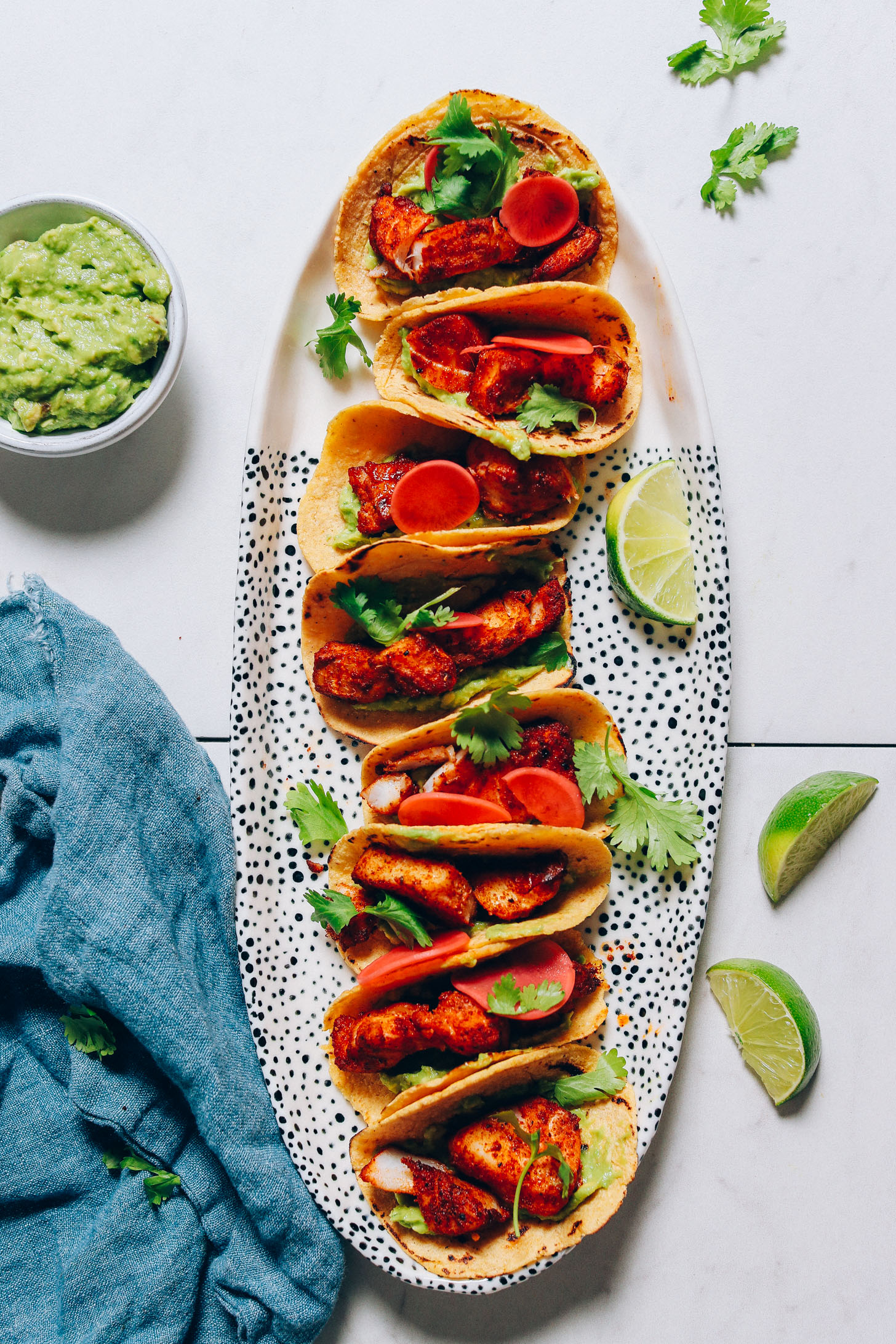 Long platter of Spicy Baked Fish Tacos with cilantro, lime, and guacamole