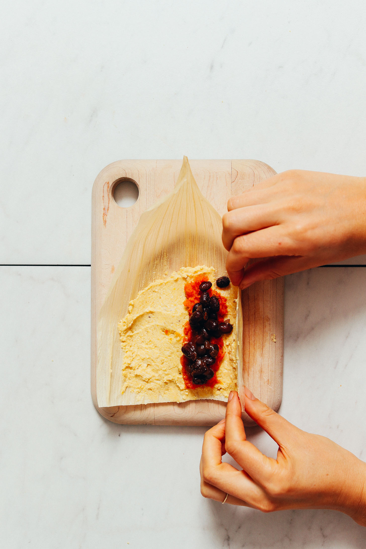 Showing how to fold a tamale over the sweet potato black bean filling