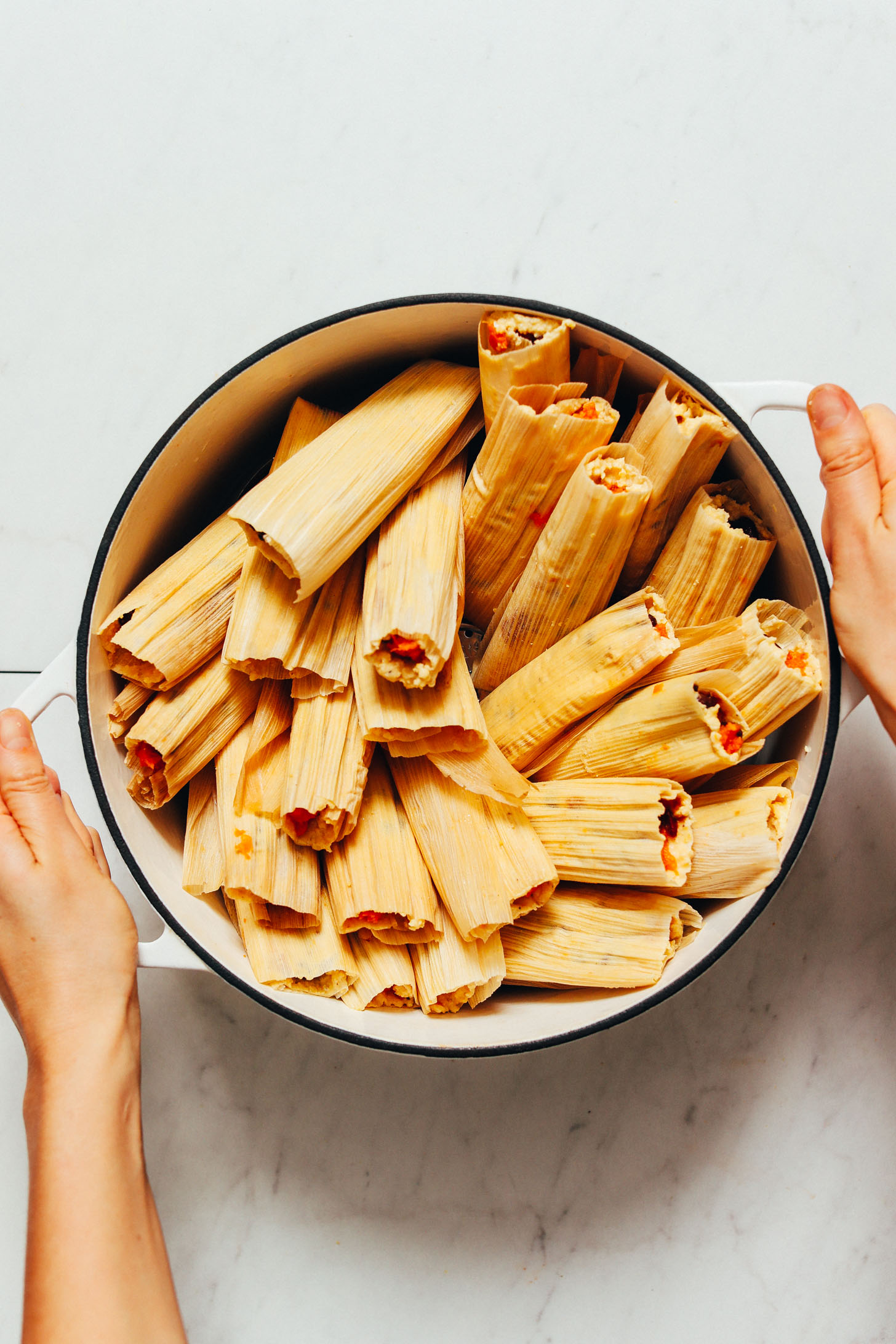 Holding a pot of homemade tamales for our tutorial on How to Make Tamales
