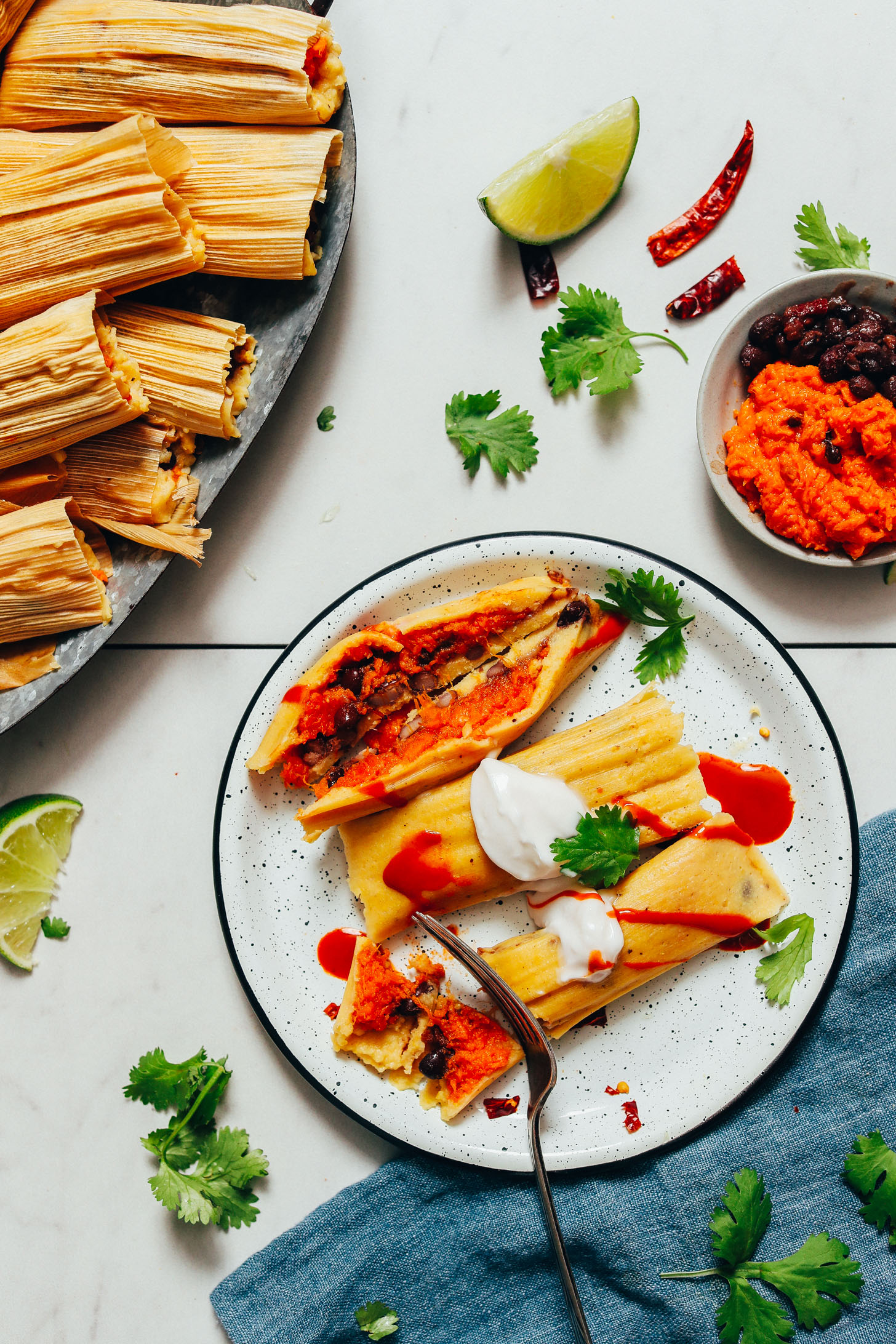 Using a fork to slice into a plate of vegan tamales