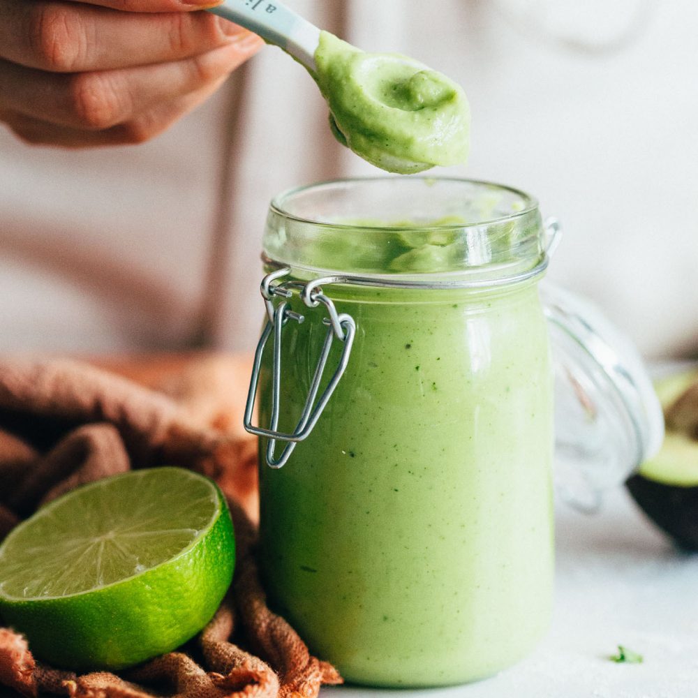 Picking up a spoonful of Avocado Aioli from a glass jar