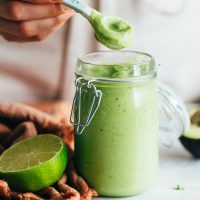 Picking up a spoonful of Avocado Aioli from a glass jar