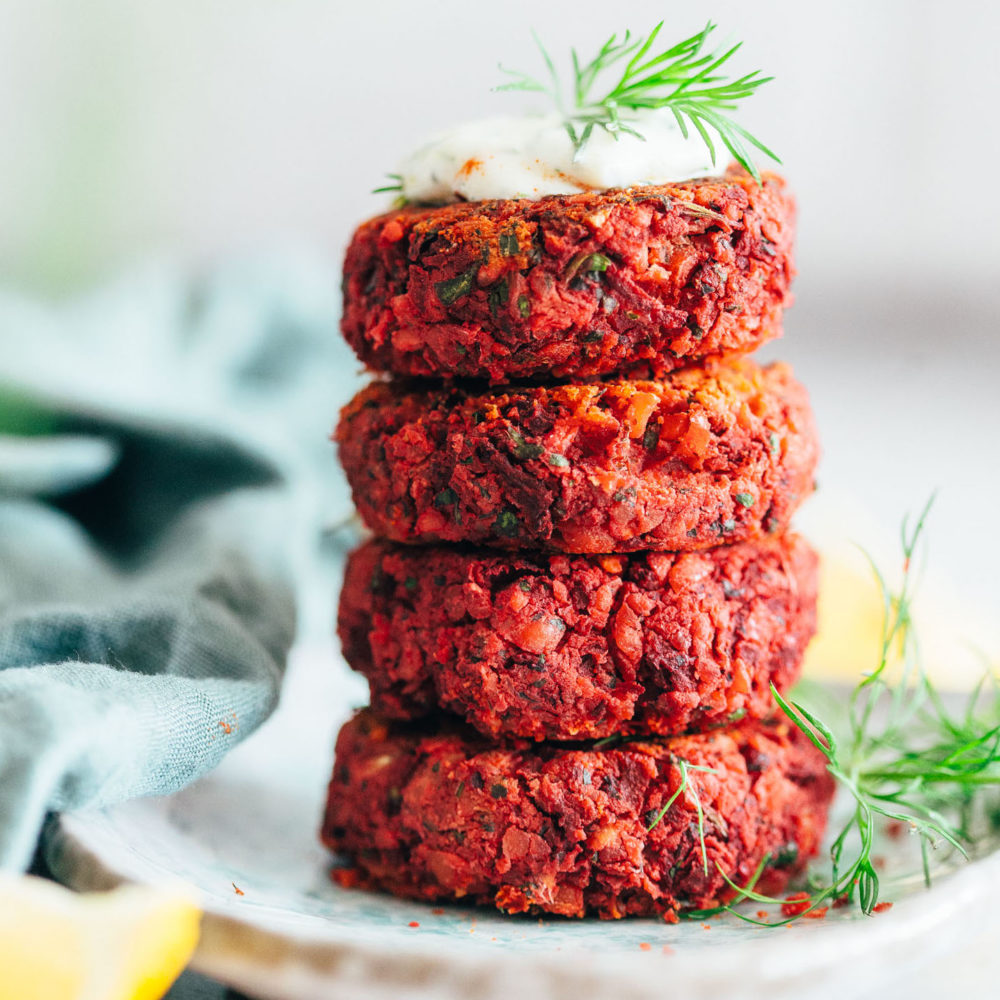 Plate with a stack of Beet Falafel topped with vegan yogurt sauce and dill