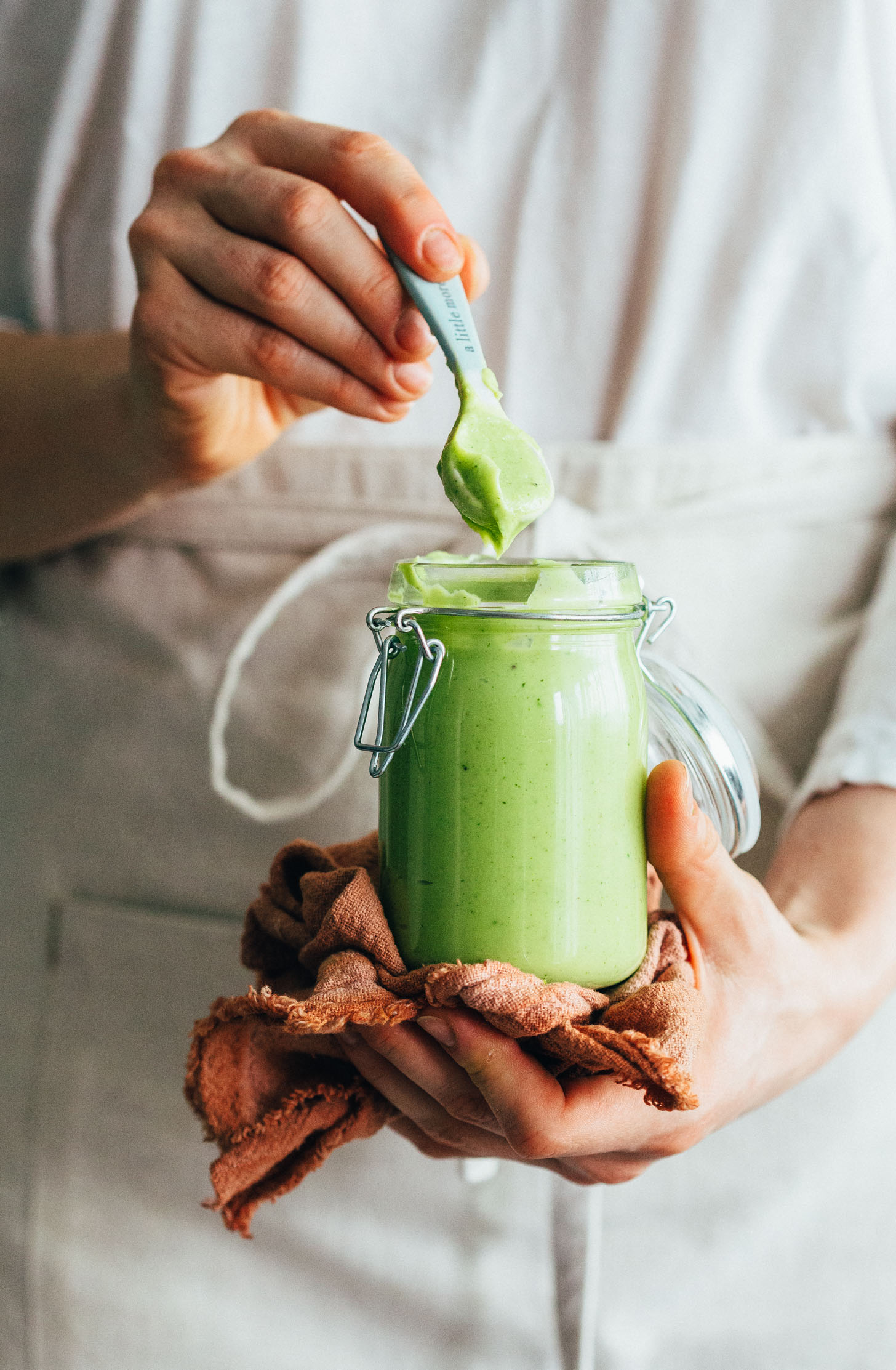 Holding a spoonful of Avocado Aioli over a jar