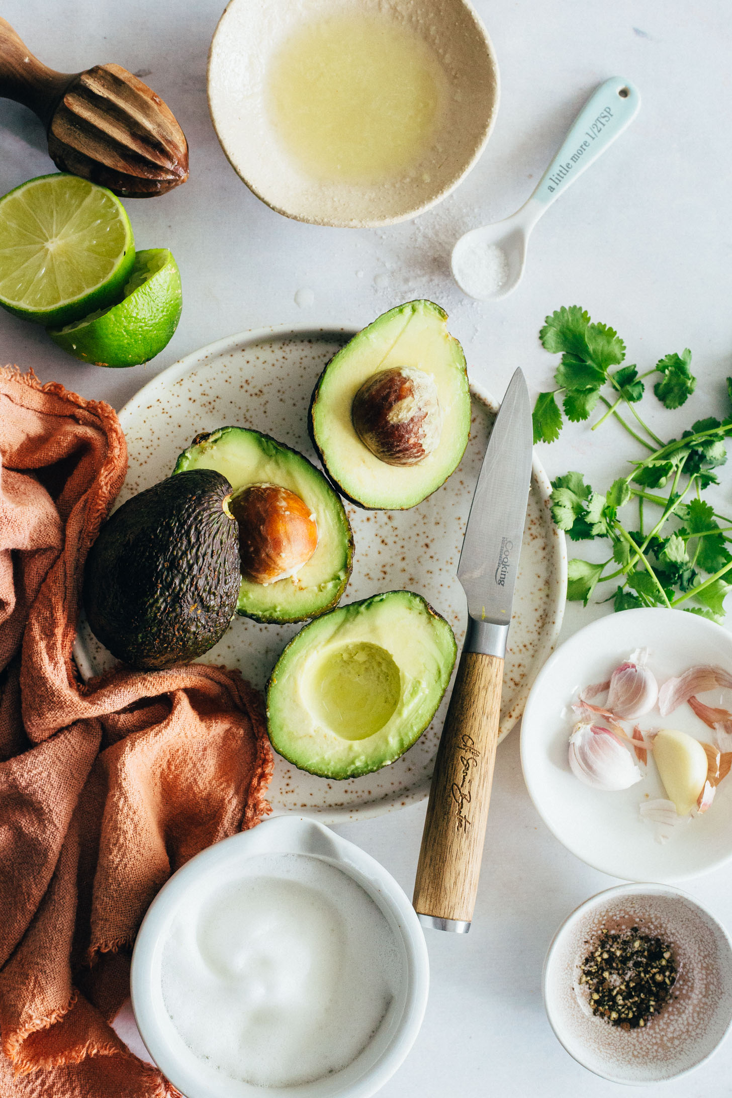 Plates and bowls of halved avocados, limes, cilantro, garlic, aquafaba, and black pepper