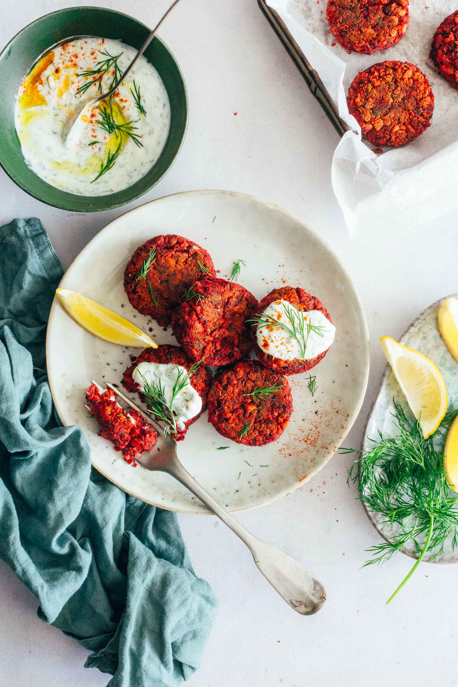 Baking sheet and plate of Beet Falafel next to a bowl of Yogurt Dill Sauce