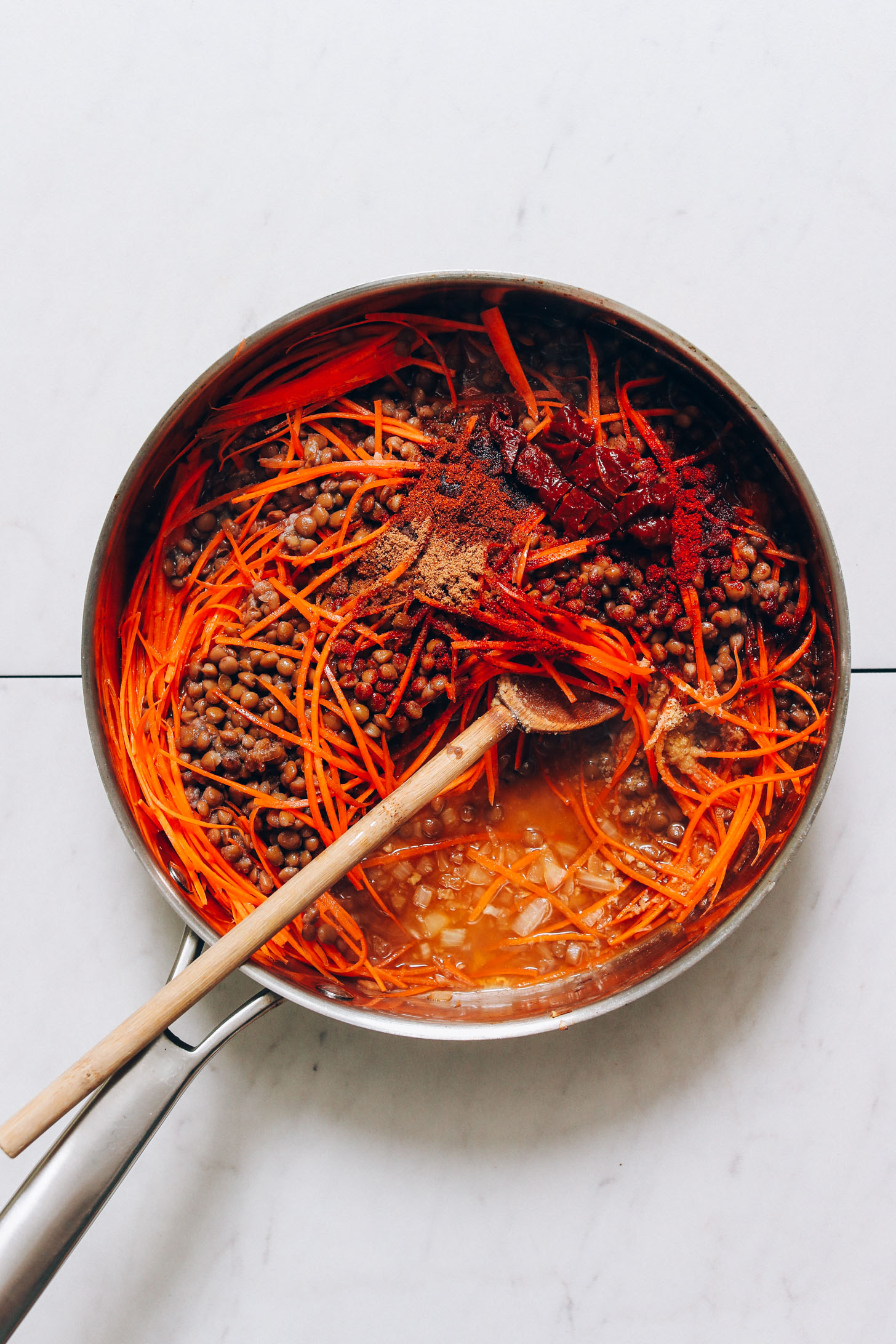 Lentils, shredded carrots, sautéed onions, and spices in a large rimmed skillet
