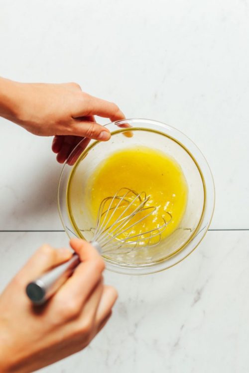 Whisking dressing ingredients in a small bowl to make homemade Lemon Vinaigrette