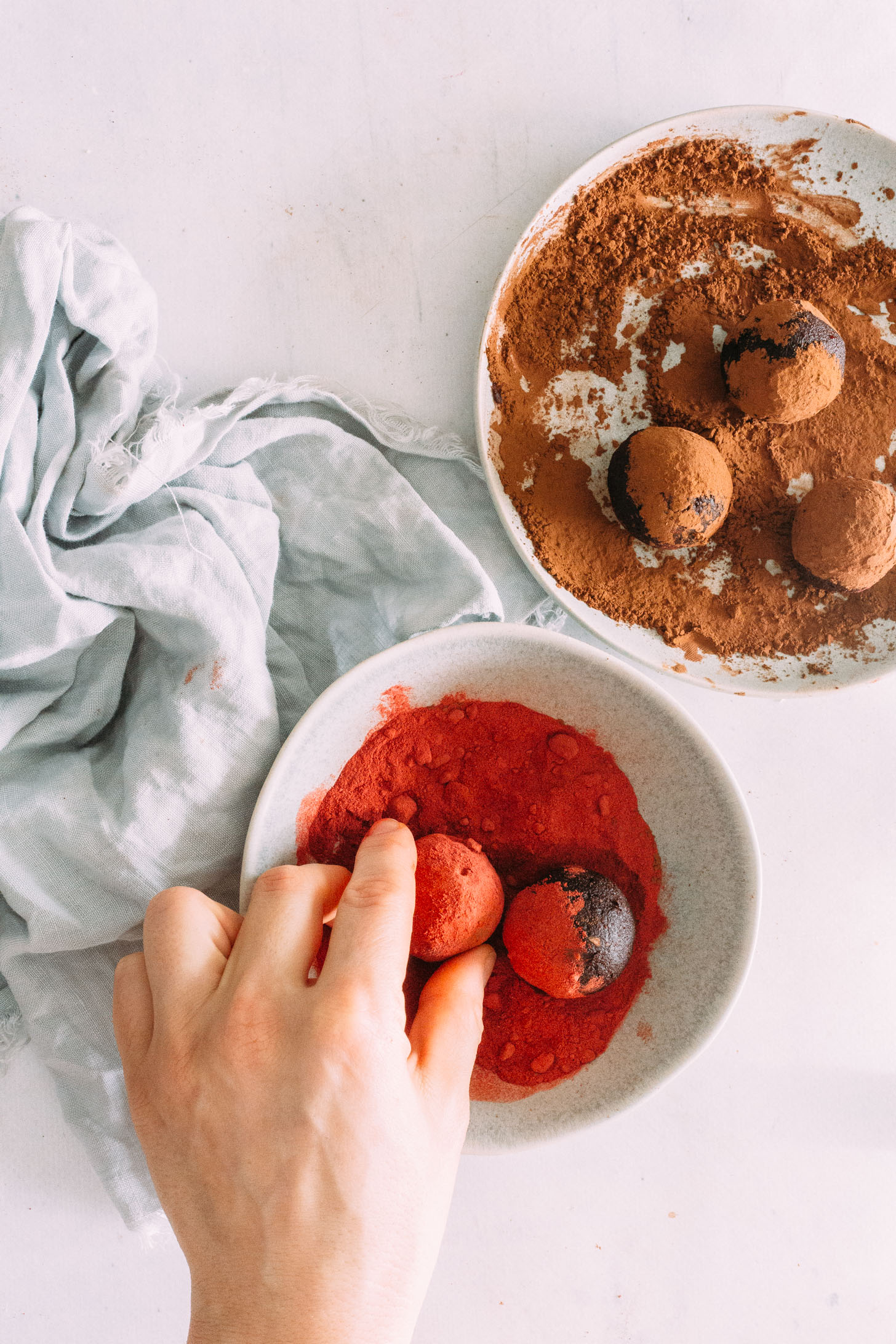 Rolling a red velvet cake bite in beet root powder