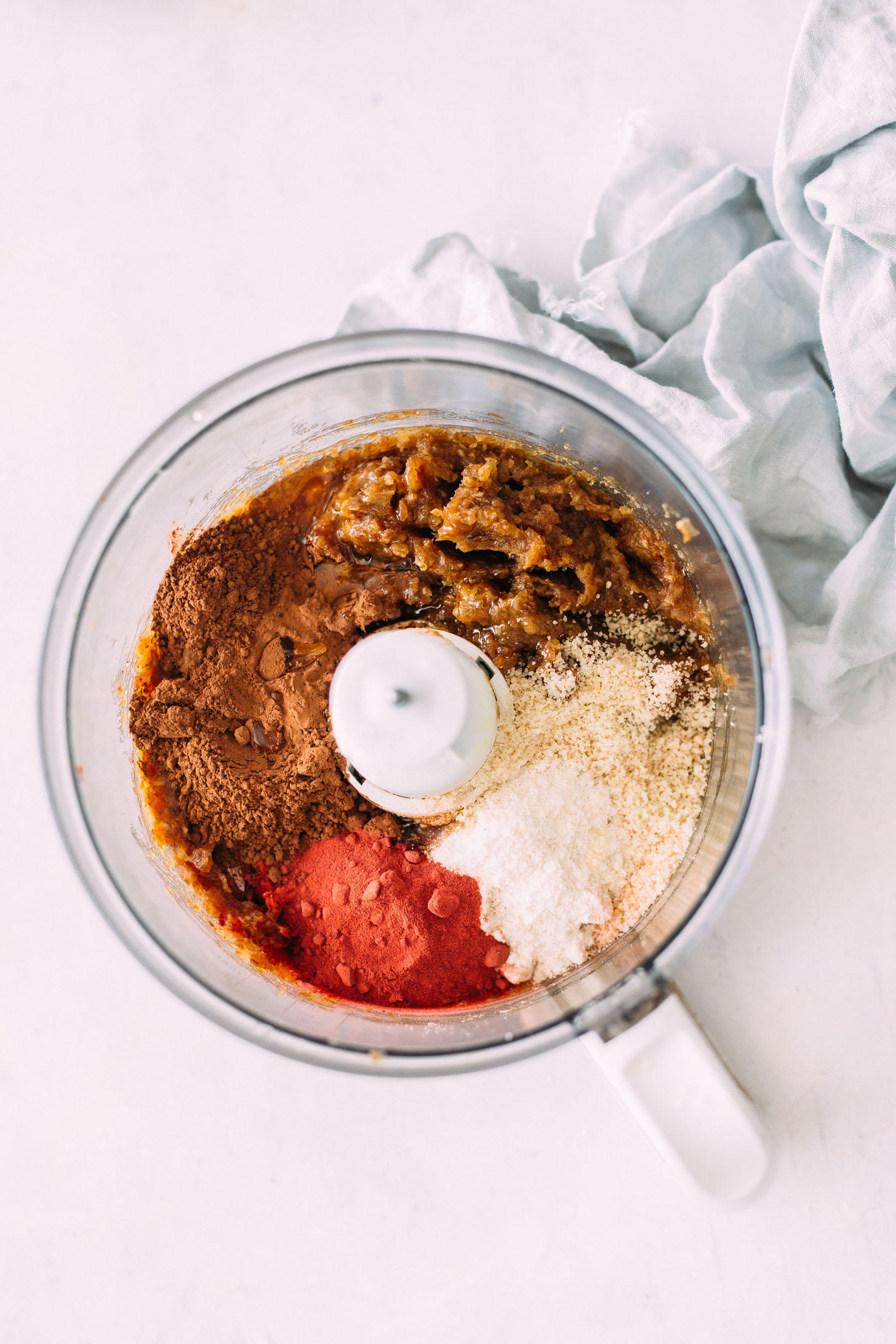 Food processor with blended dates, cacao powder, coconut flour, almond flour, and beet powder