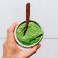 Bowl of green chutney with a small wooden spoon in it