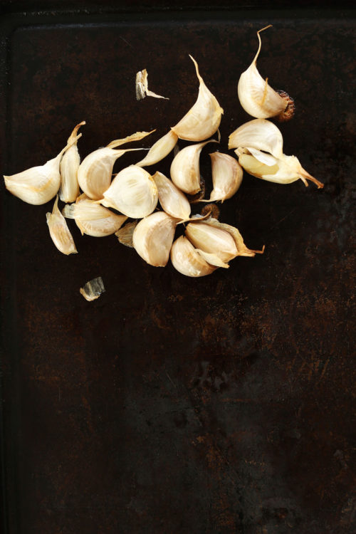 Cloves of freshly roasted garlic on a baking sheet for our tutorial on How to Roast Garlic