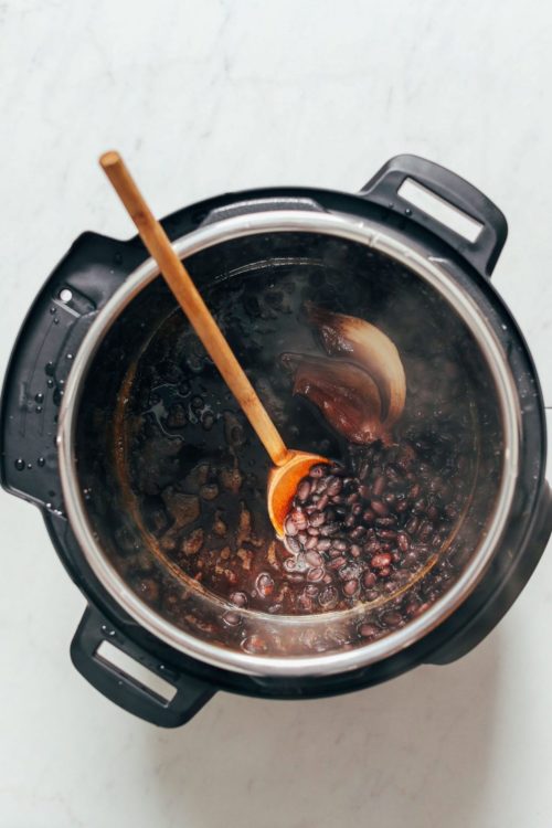 Wooden spoon in a pot of freshly cooked Instant Pot Black Beans